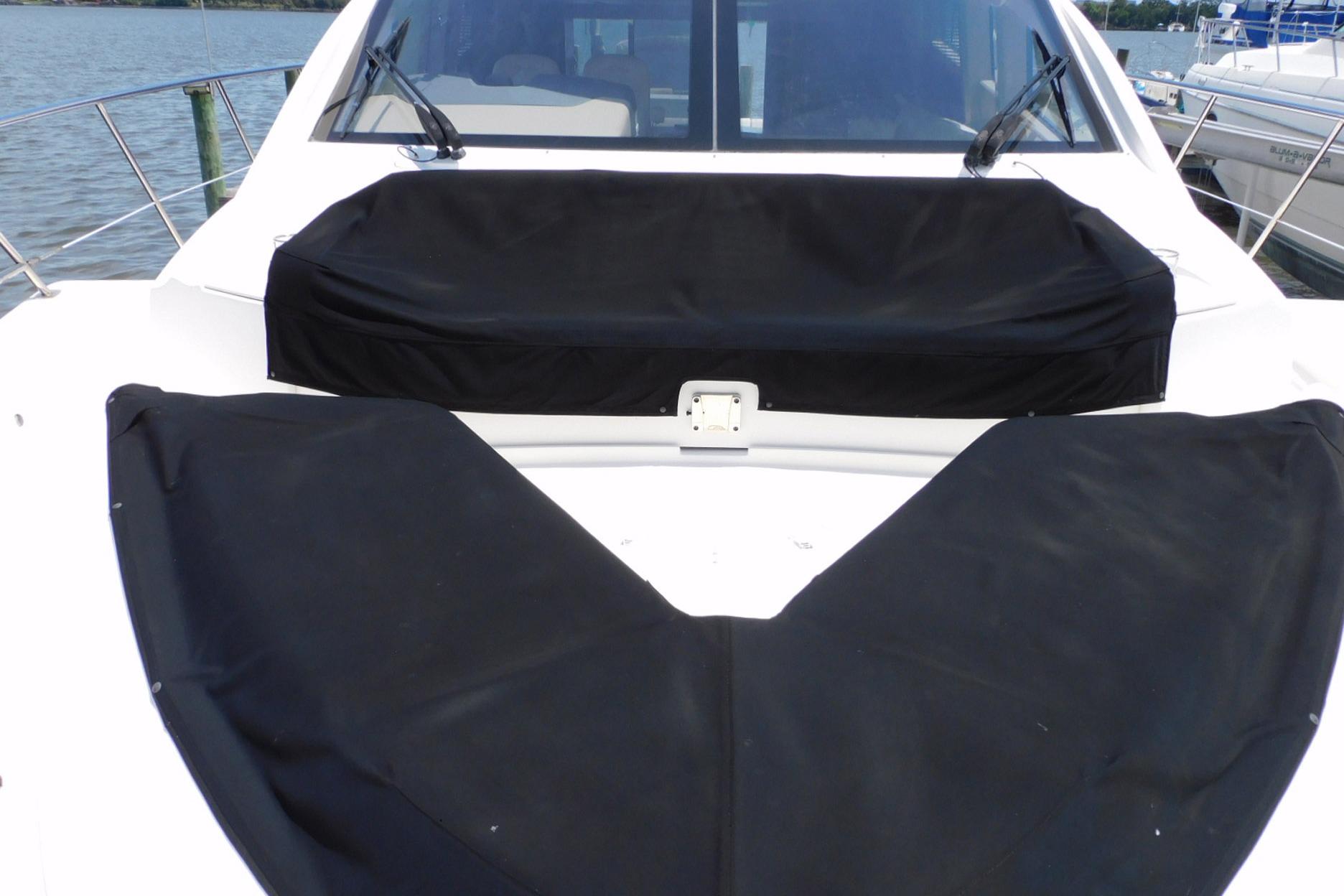 2019 Sea Ray L550 yacht with black covers on deck, docked by the water.