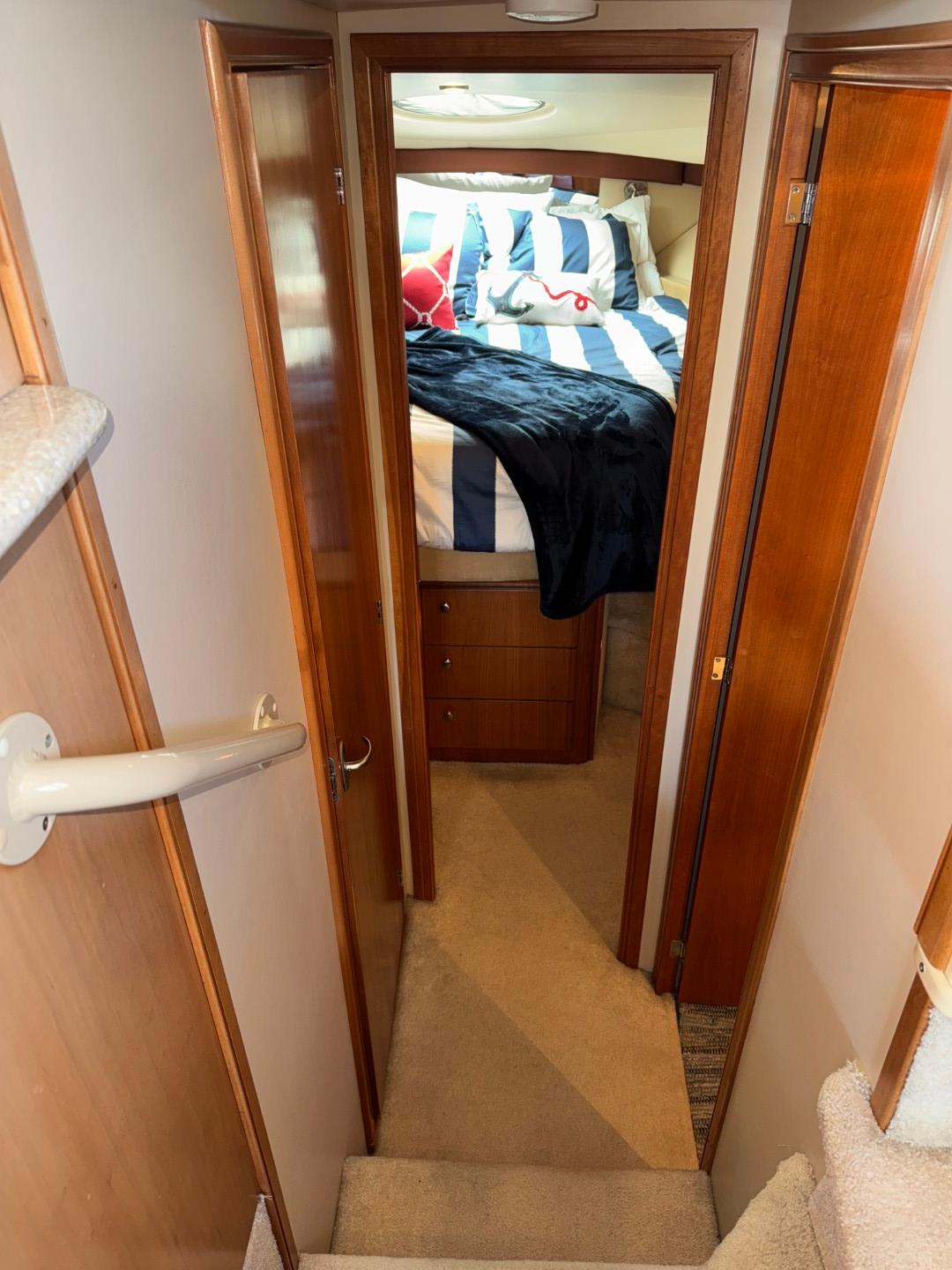 Interior of 2003 Meridian 381 Sedan yacht, featuring cozy bedroom with striped bedding.