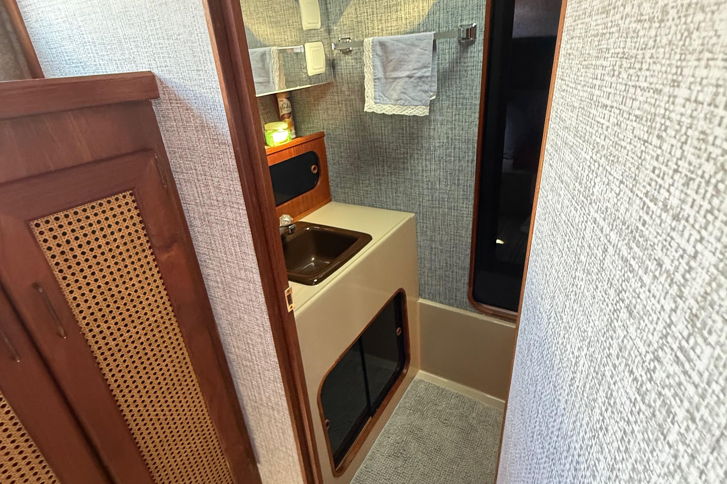 1983 Bayliner 3870 Motoryacht bathroom with sink, towel rack, and wooden cabinetry.
