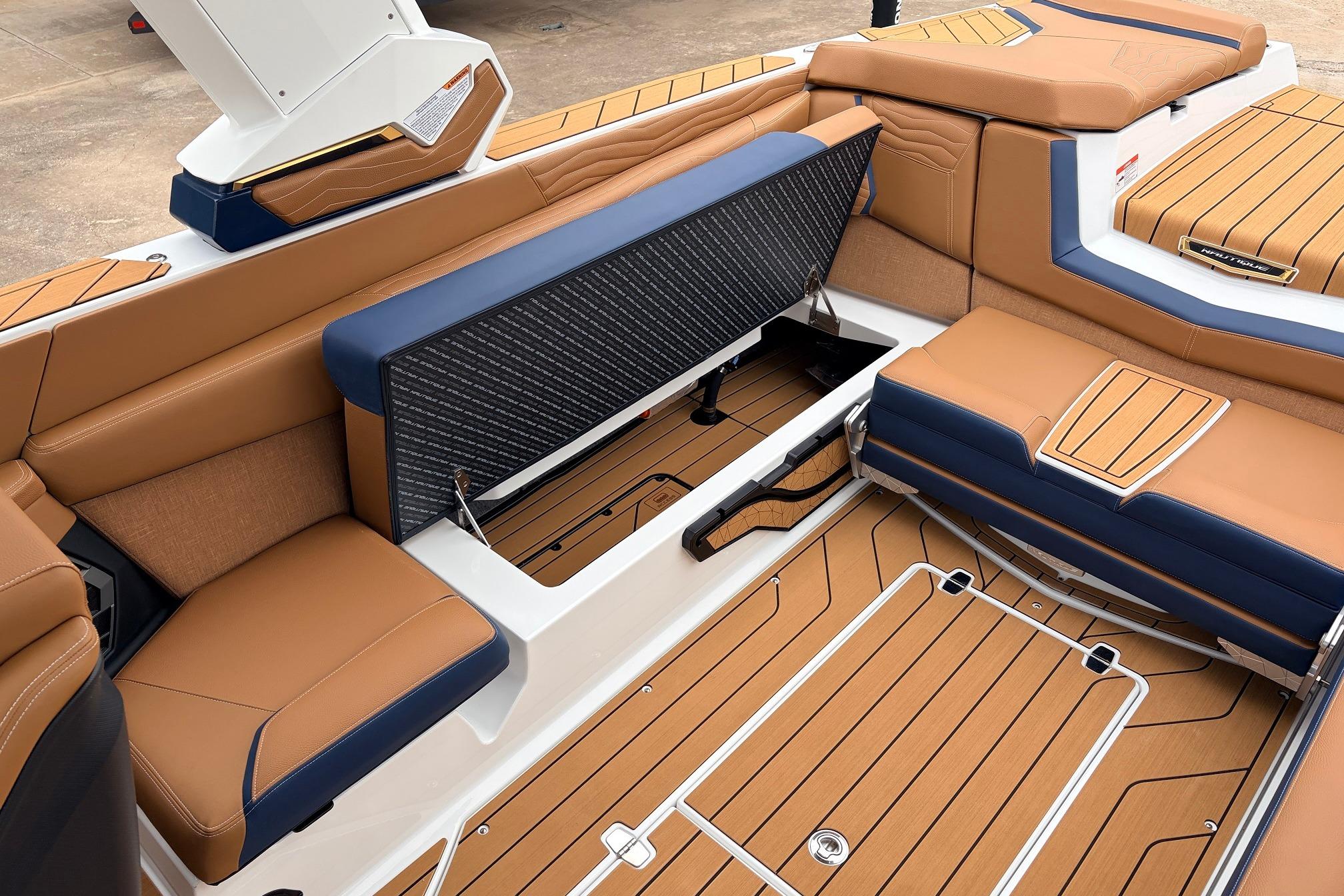 2026 Nautique Super Air Nautique G25 interior with tan and blue seating, open storage compartment.