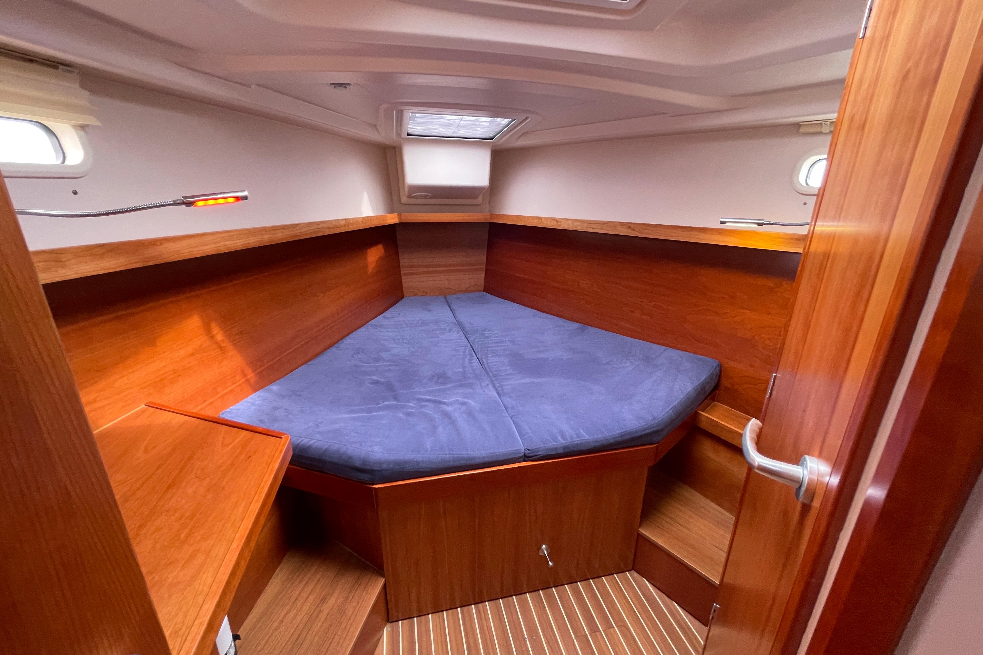 Cozy cabin interior of 2014 Hanse 415 yacht with wooden finish and blue bedding.