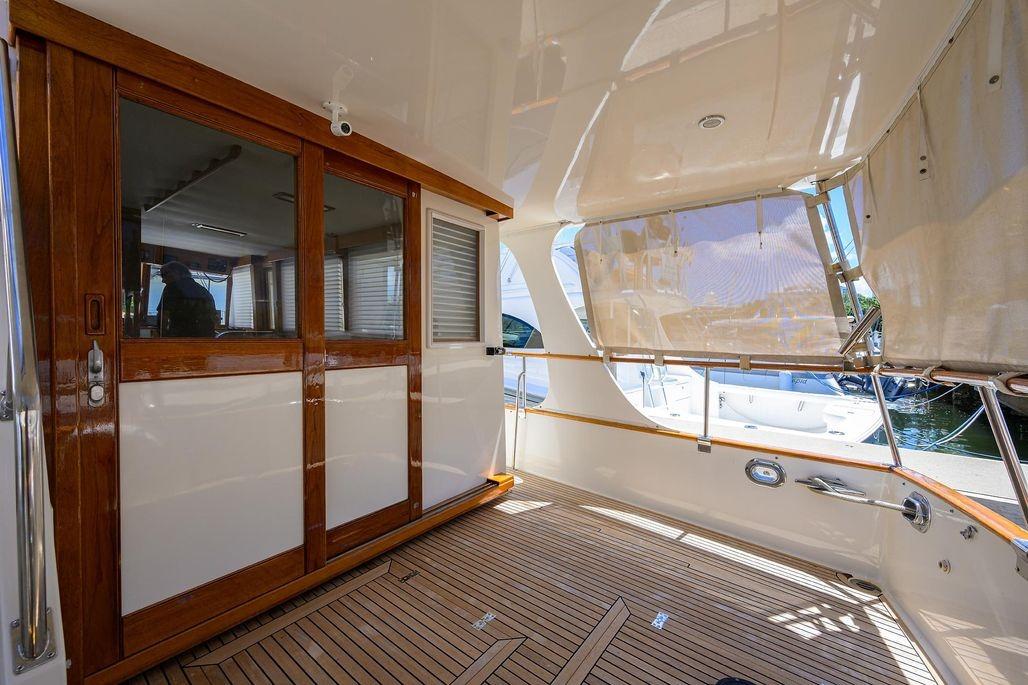 Spacious deck of 1999 Grand Banks 42 Europa yacht with wooden accents and sliding doors.