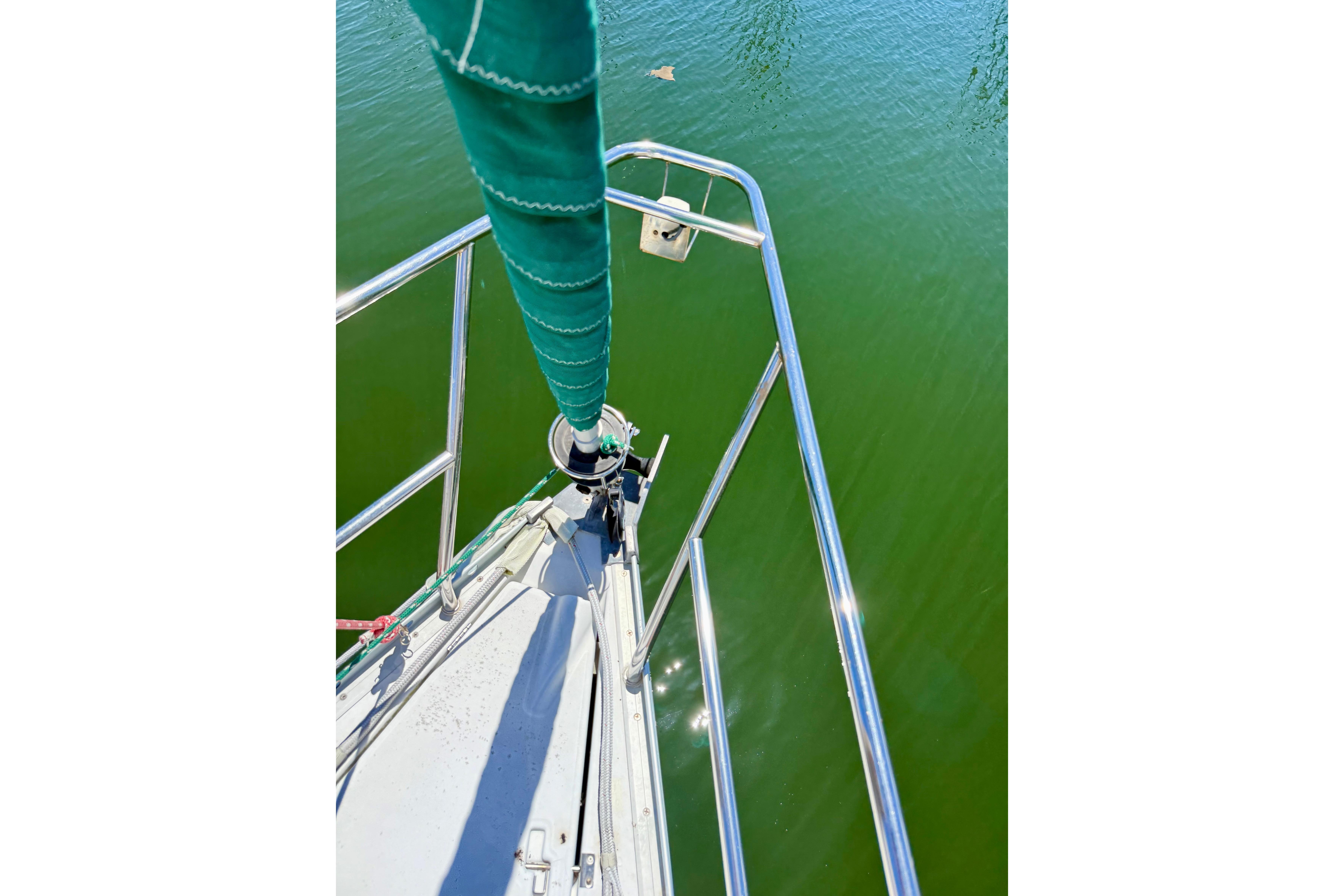 Bow view of 2002 Beneteau Oceanis Clipper 311 sailboat on calm green water.