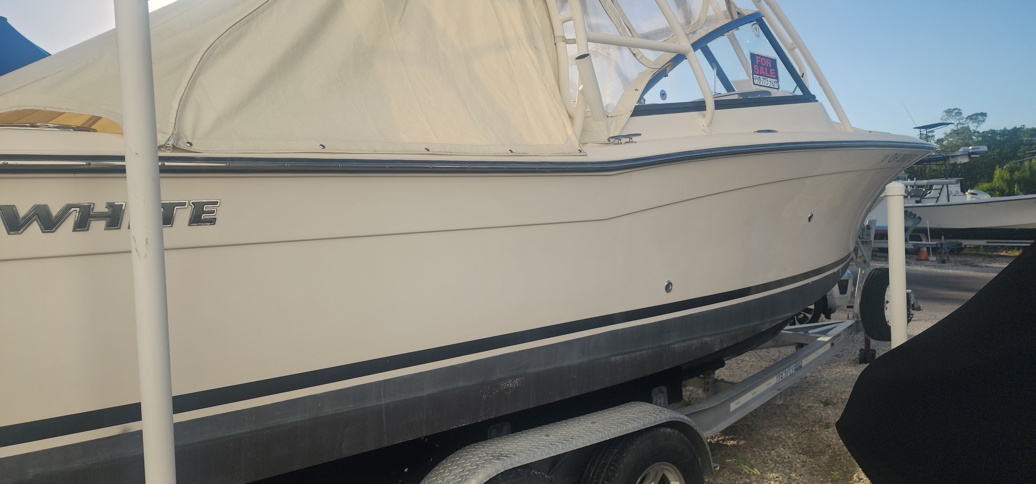 A 2015 Grady-White Freedom 275 boat on a trailer, partially covered with a tarp.