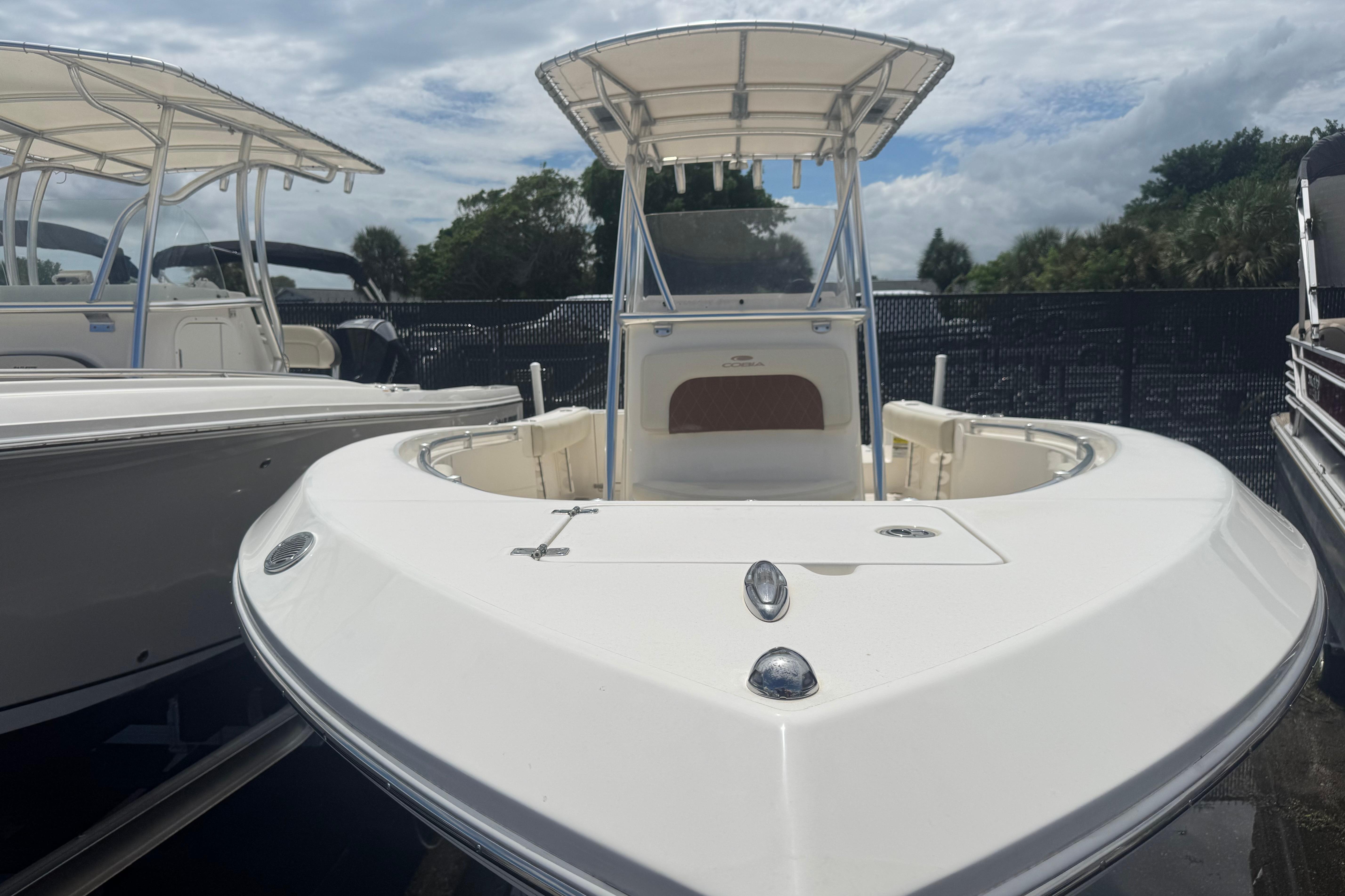 2022 Cobia 237 Center Console boat with T-top, docked under cloudy sky.