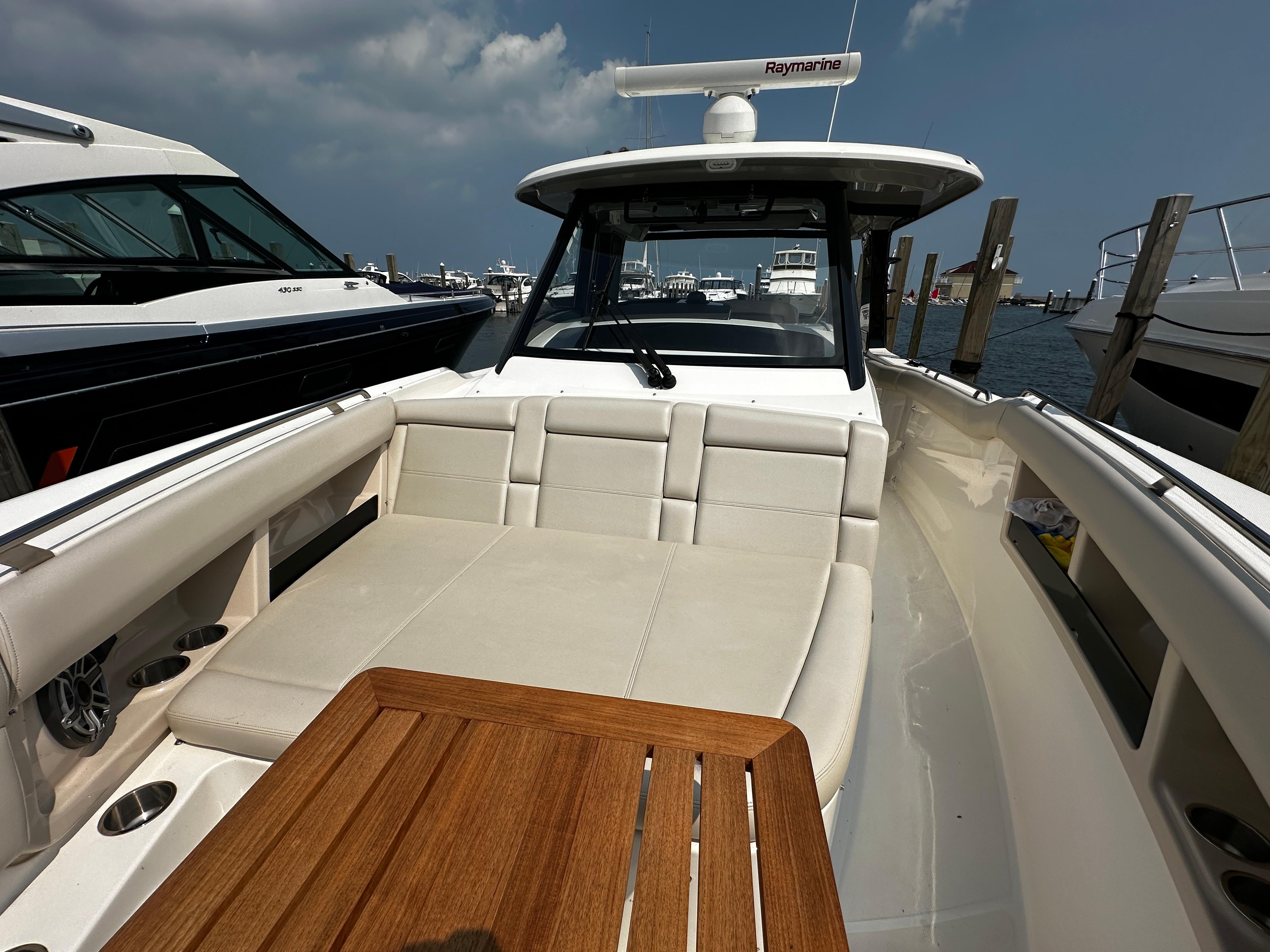 2022 Boston Whaler 350 Realm boat with spacious seating and wooden table, docked at marina.