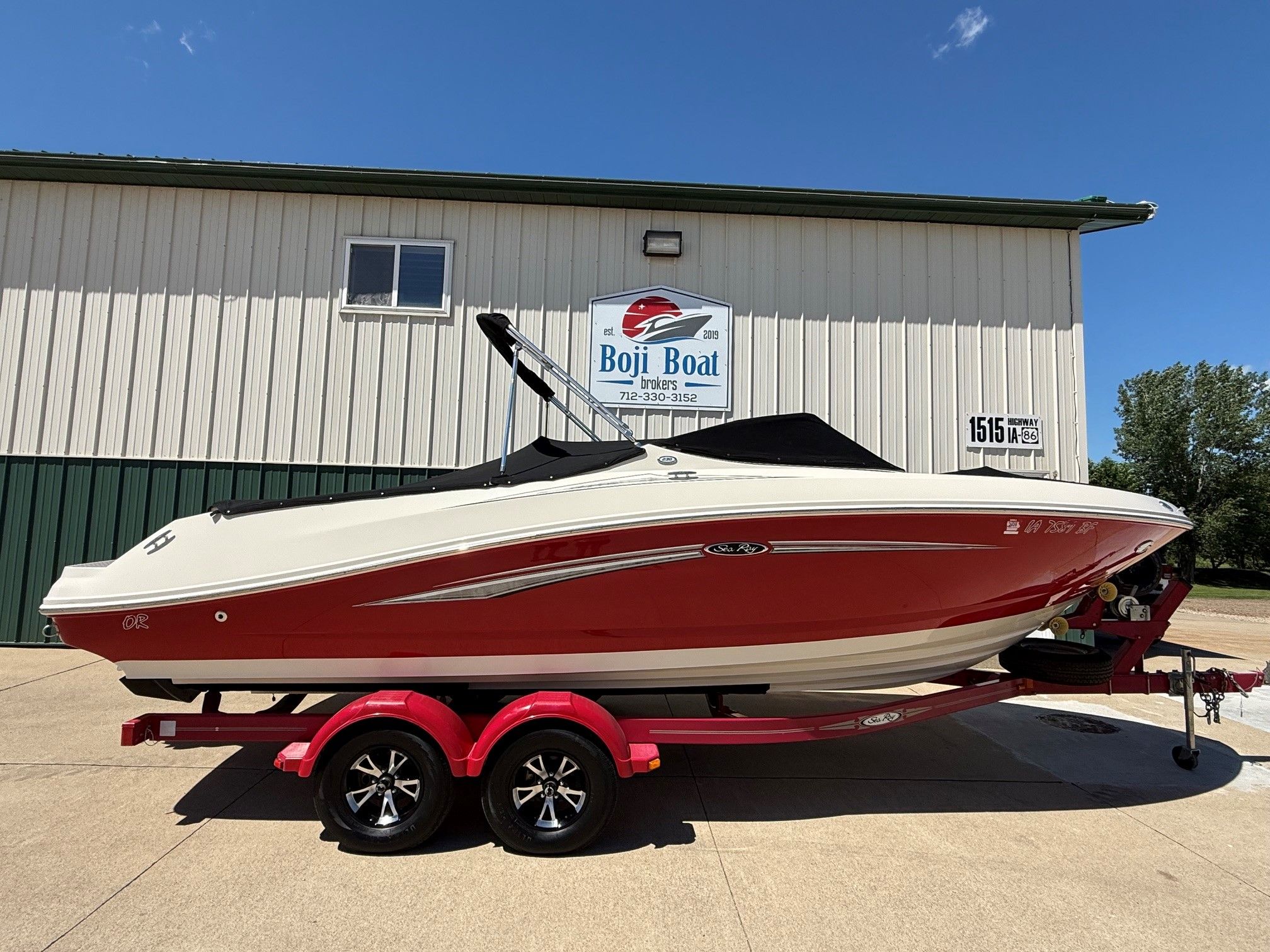 2007 Sea Ray 230 Select boat on trailer in front of building.