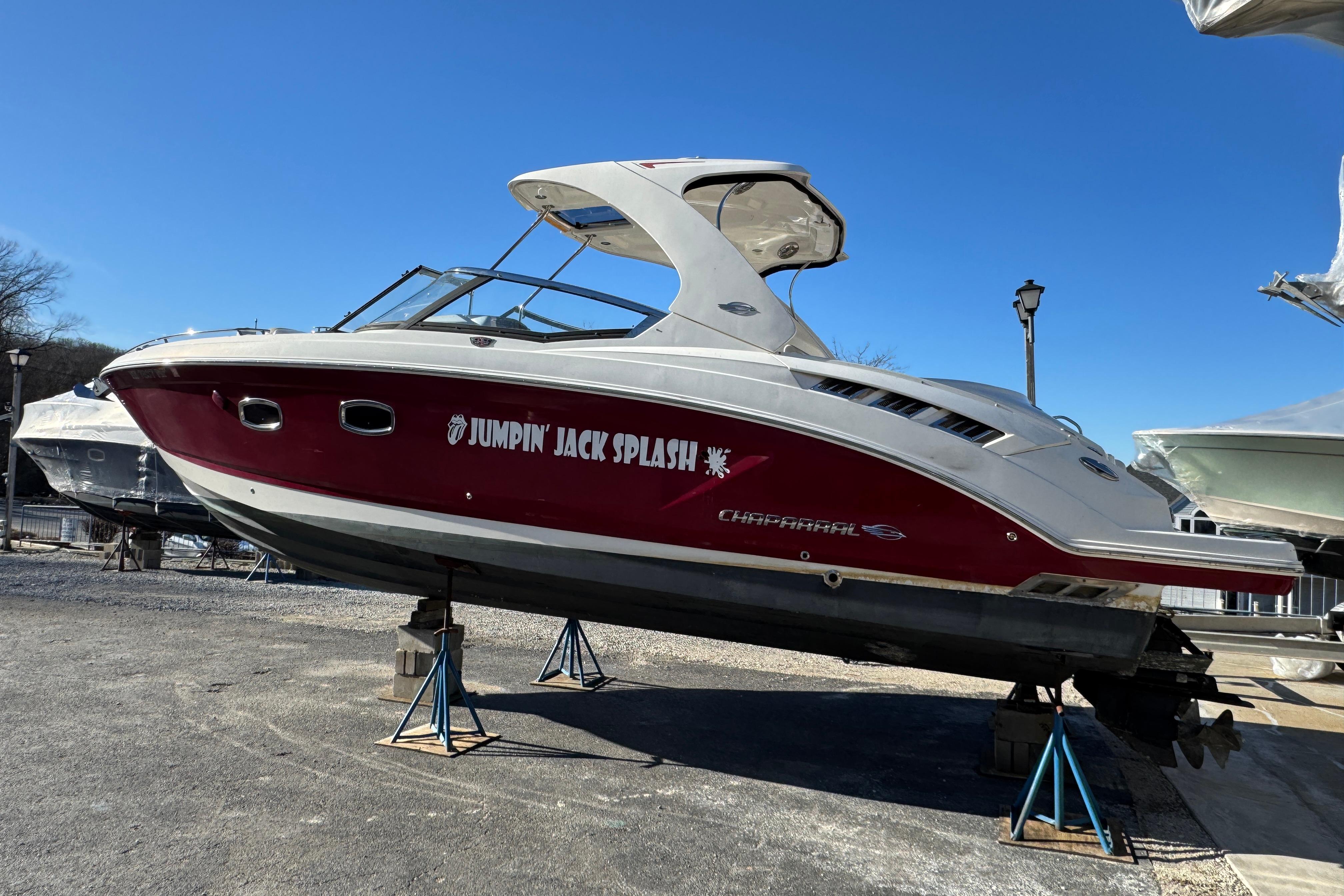 2012 Chaparral 327 SSX boat named "Jumpin' Jack Splash" on stands, side view.