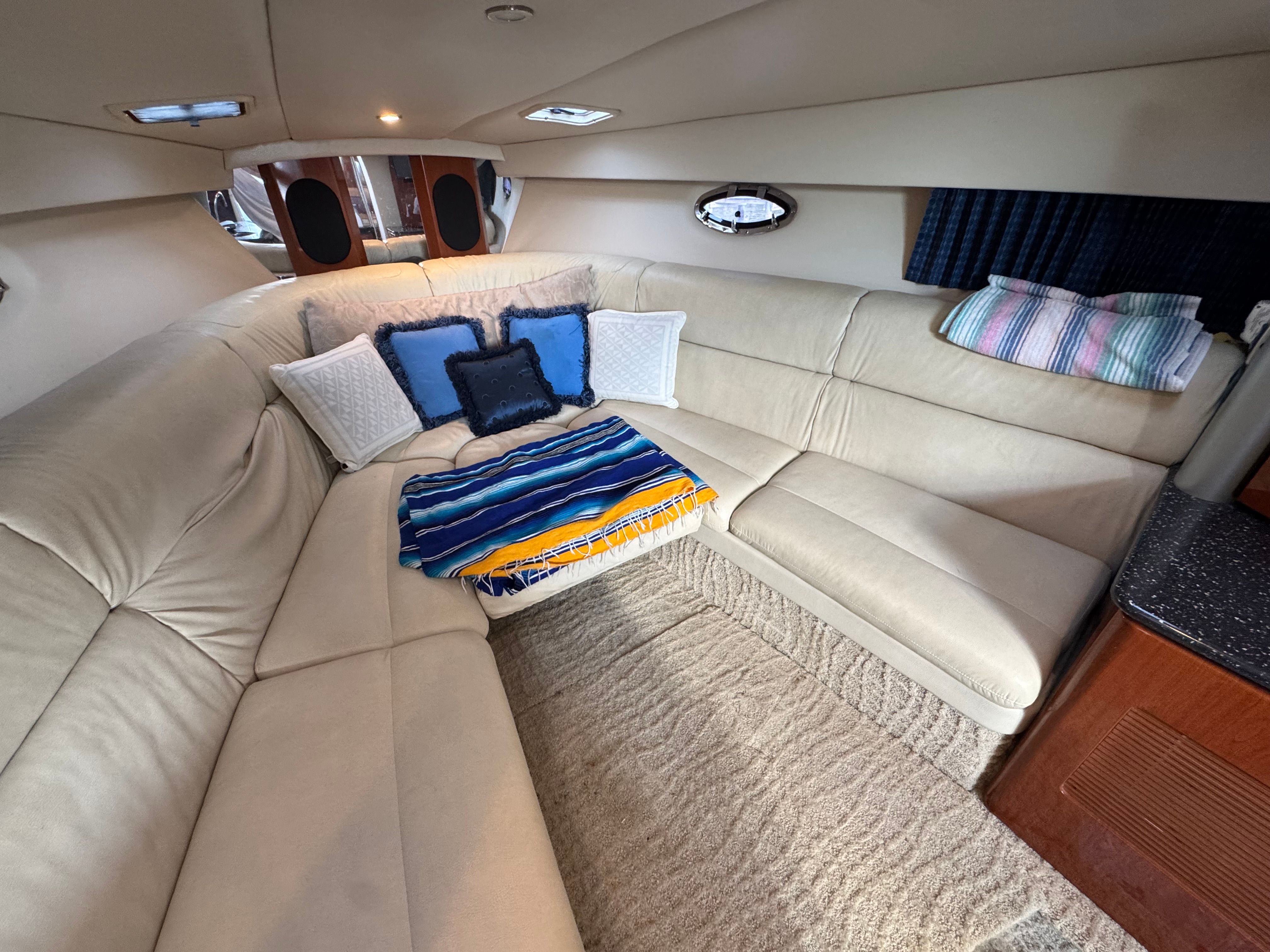 Interior of a luxury yacht with beige sofa and colorful cushions.