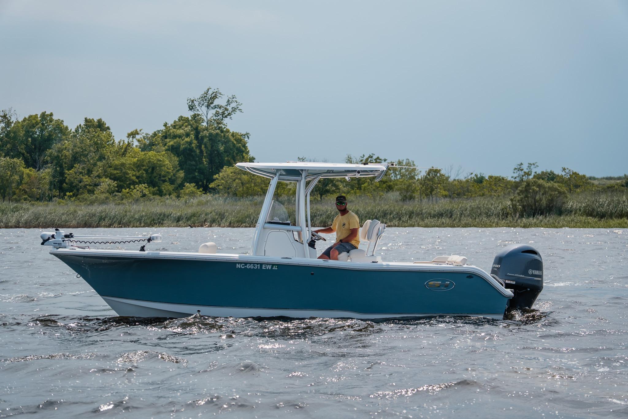 2022 Sea Hunt Ultra 229 boat cruising on a lake with lush greenery in the background.
