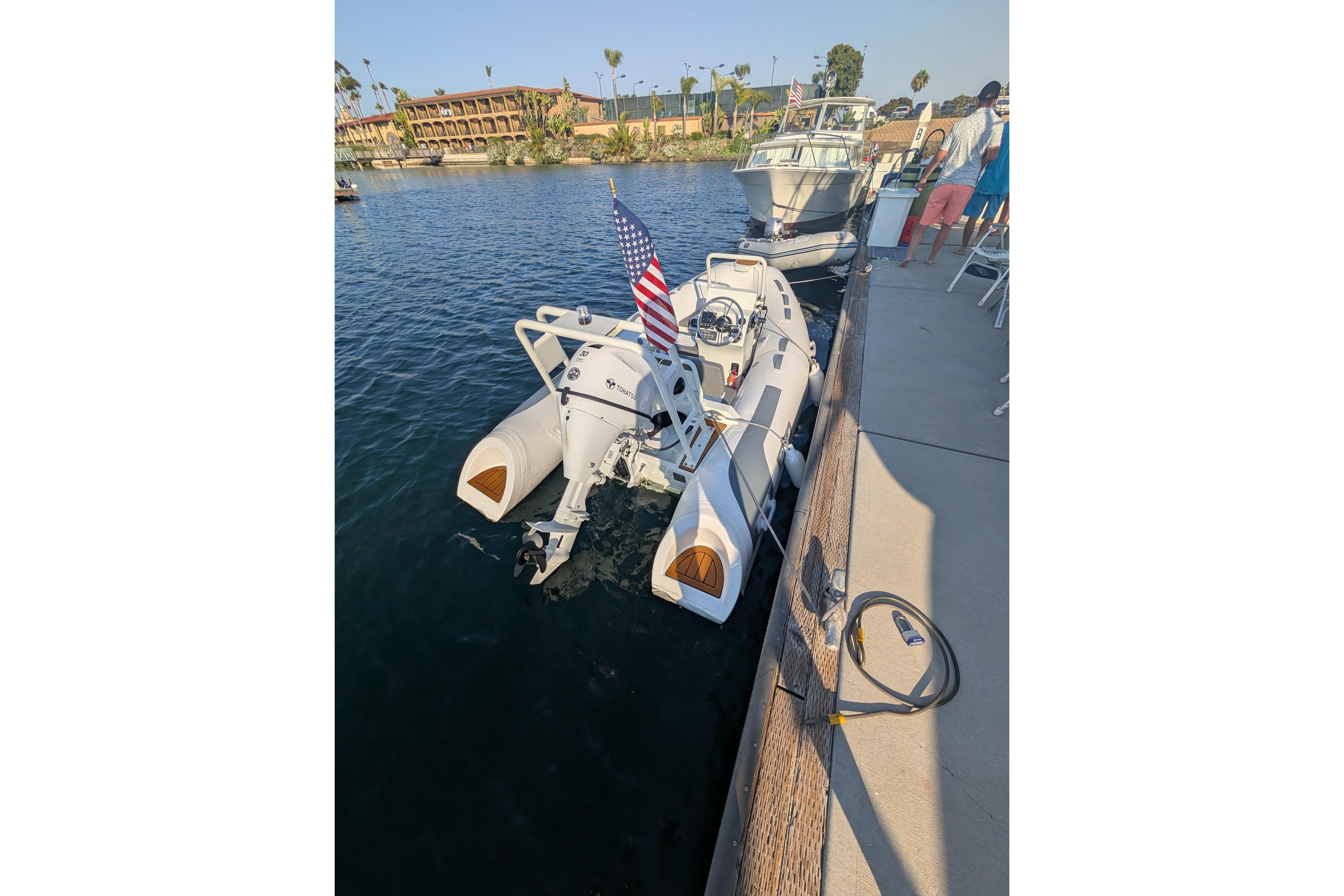 2027 Tide Craft San Juan 11 boat docked, featuring an American flag and calm waters.