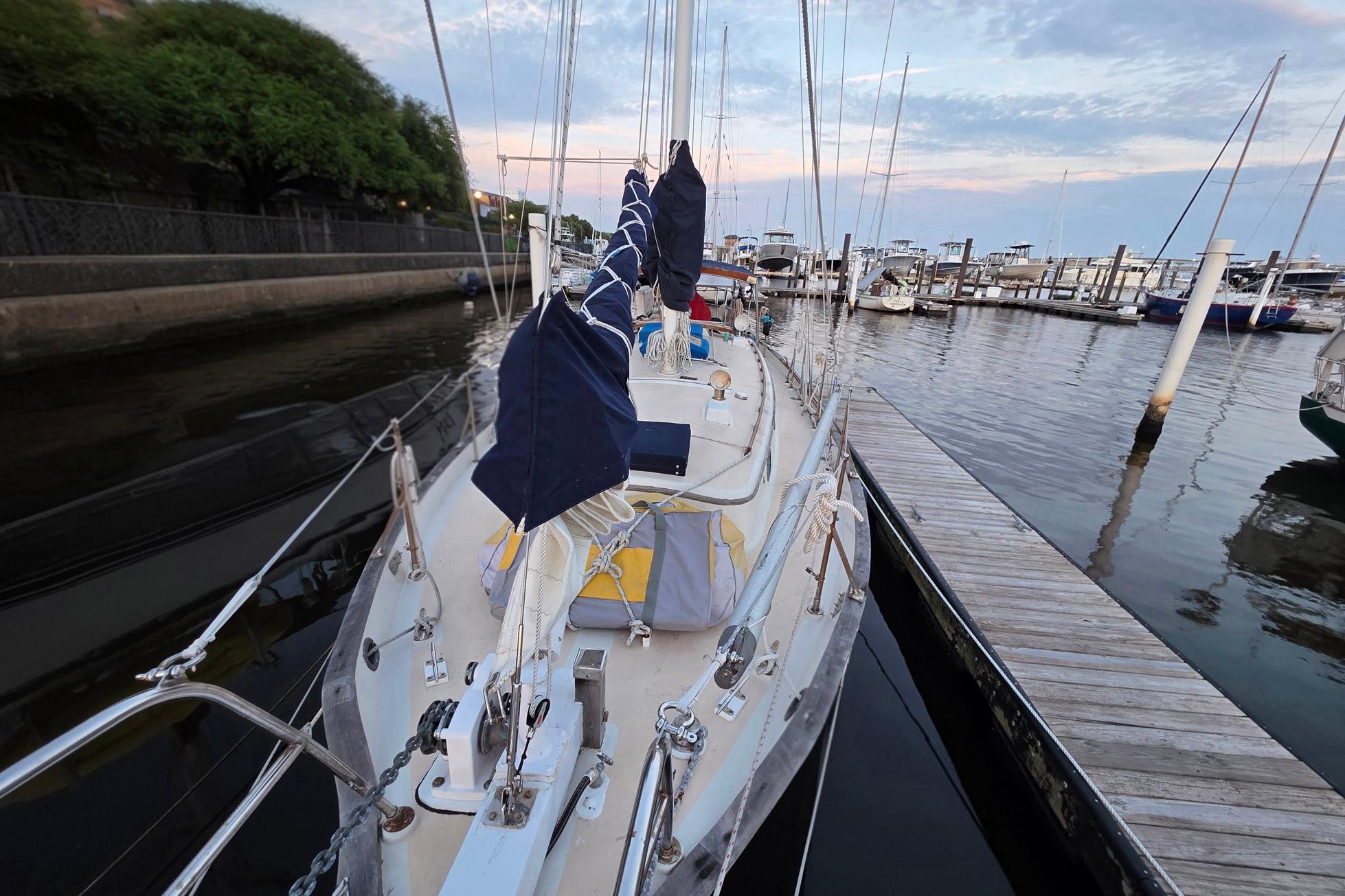 1982 Tayana 37 sailboat docked at marina, surrounded by calm water and other boats.