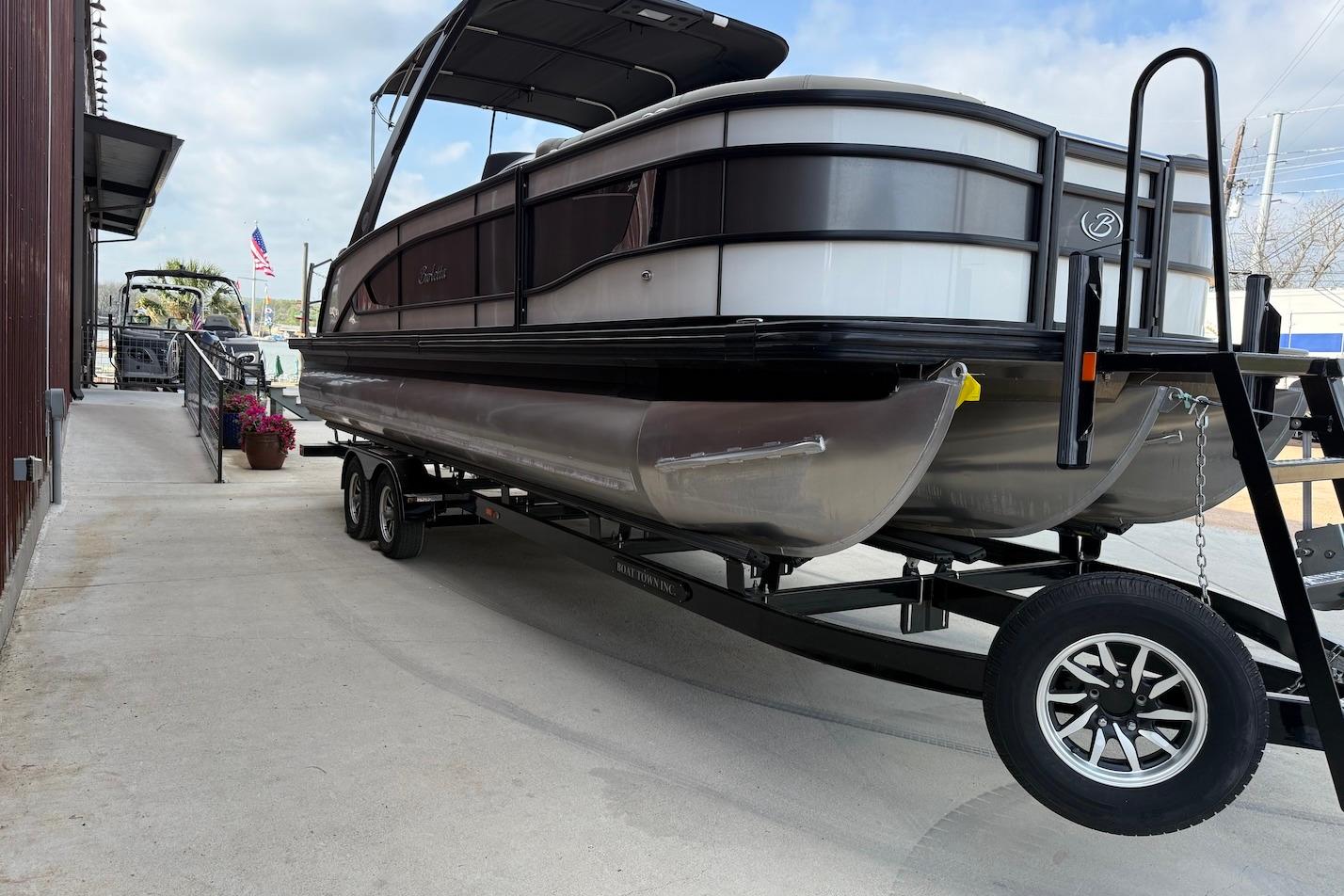 2022 Barletta LUSSO 25UEA pontoon boat on trailer, parked near a building.