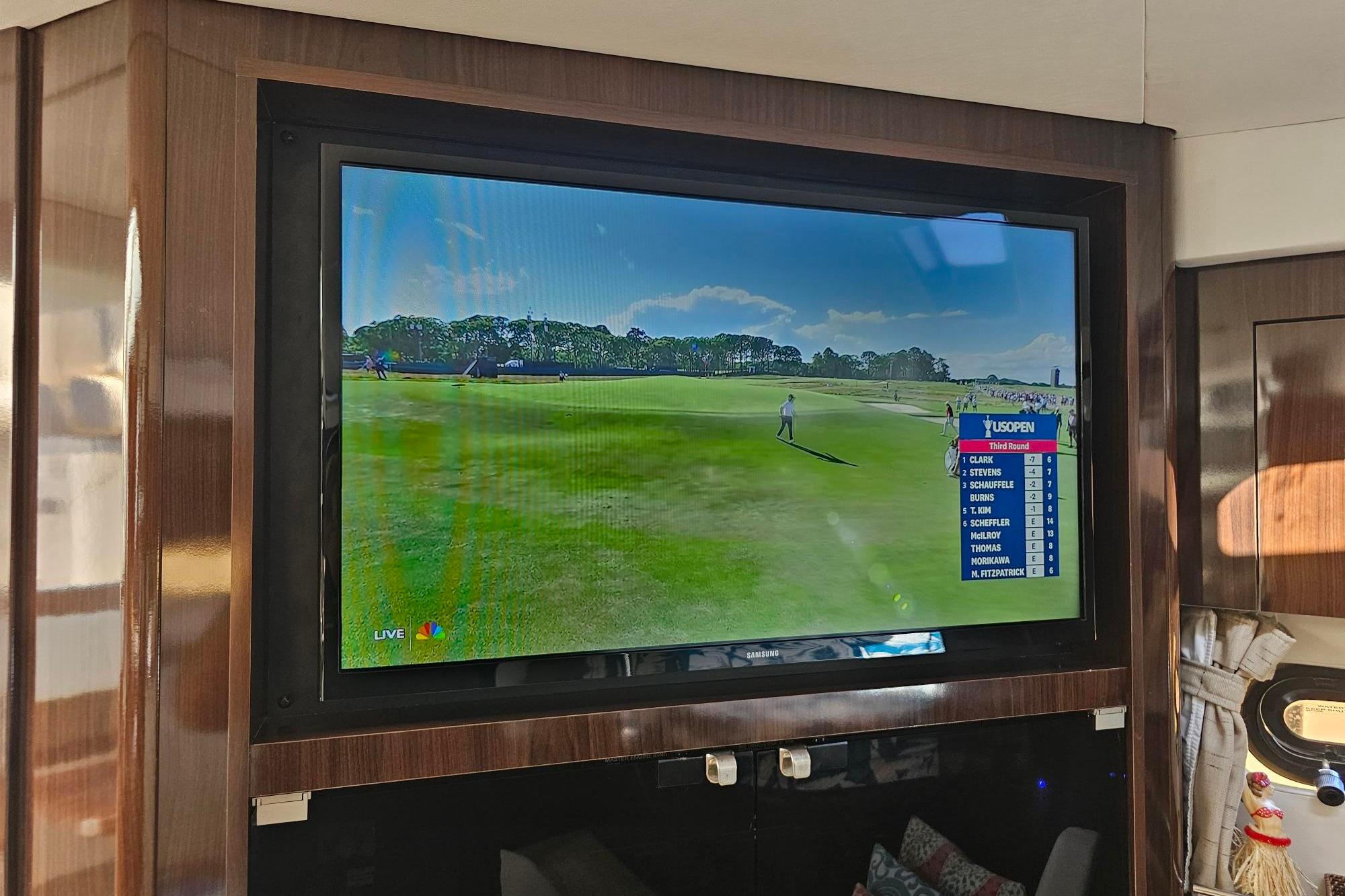 Flat-screen TV showing golf tournament inside 2016 Sea Ray Sundancer 350 yacht.
