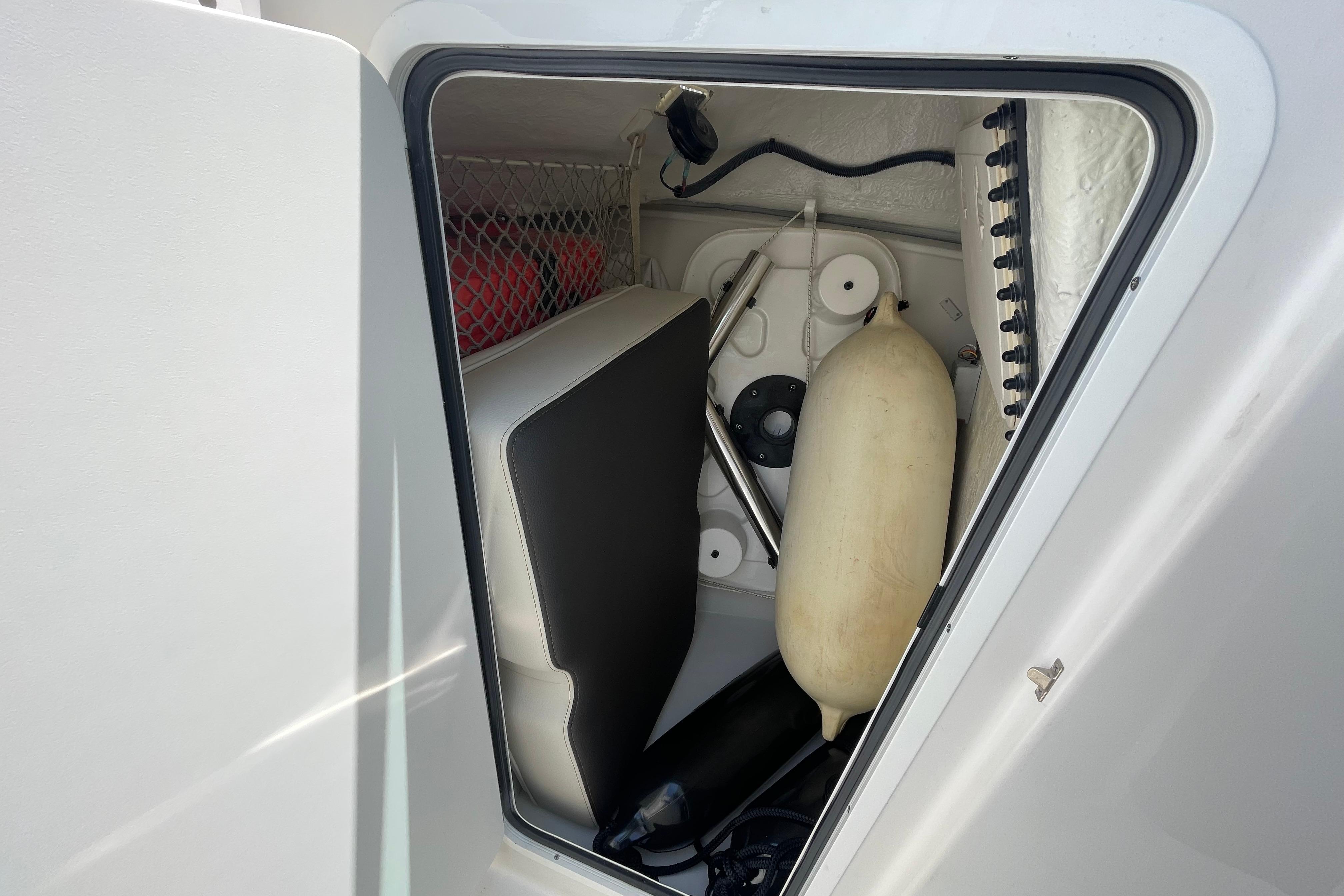 Storage compartment in a 2022 Sailfish 245 DC boat, featuring various marine equipment.