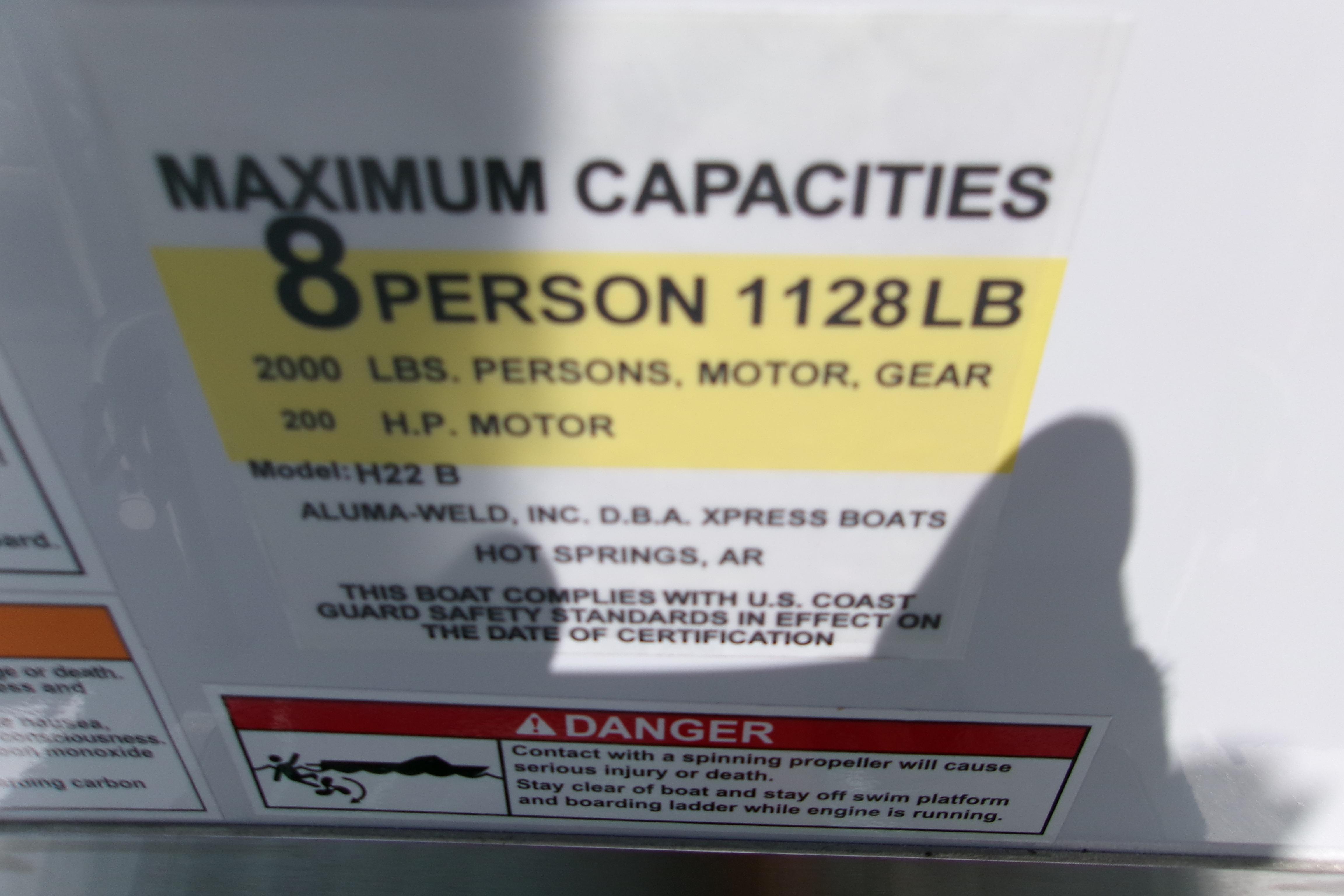 2027 Xpress H22B Bay boat capacity label: 8 persons, 1128 lbs, 200 HP motor.