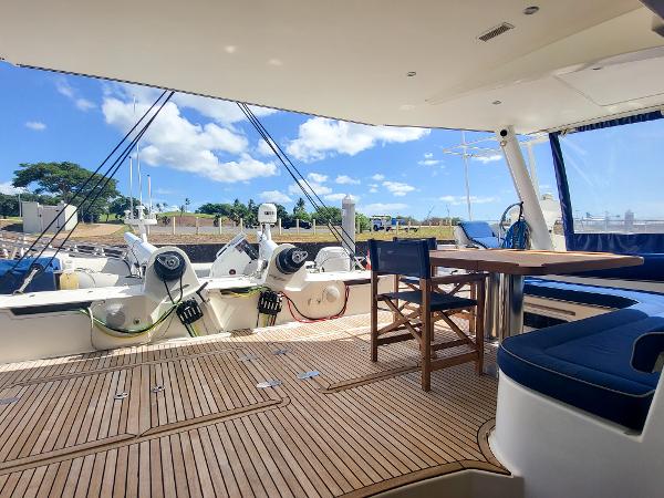 Catana 65 yacht 2009 model, spacious deck with seating and table, docked under clear blue sky.