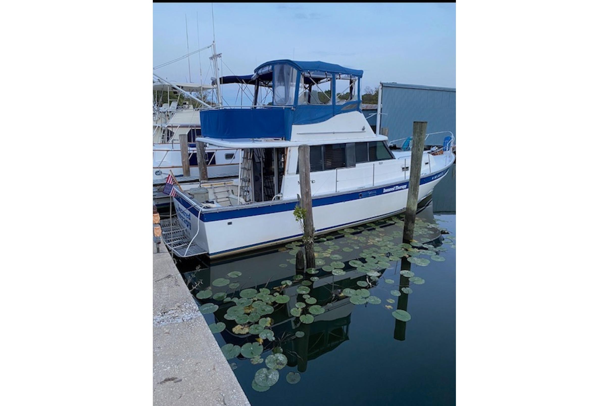 1978 Mainship 34 Trawler docked, surrounded by lily pads, with blue canopy.