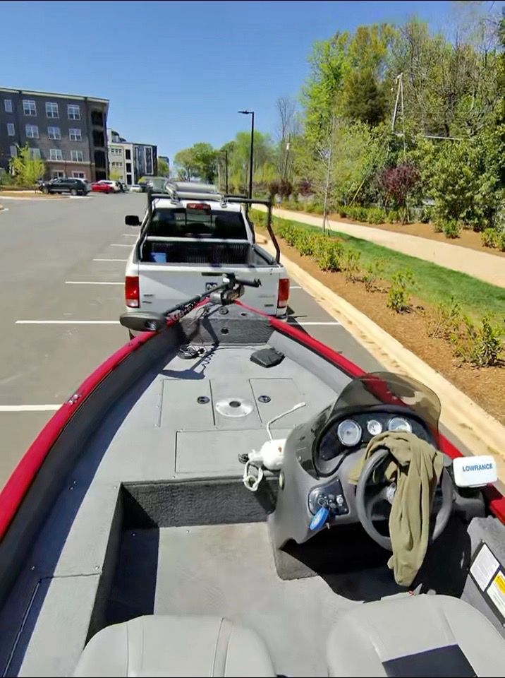 A 2019 Tracker Super Guide V-16 SC boat on a trailer in a parking lot.