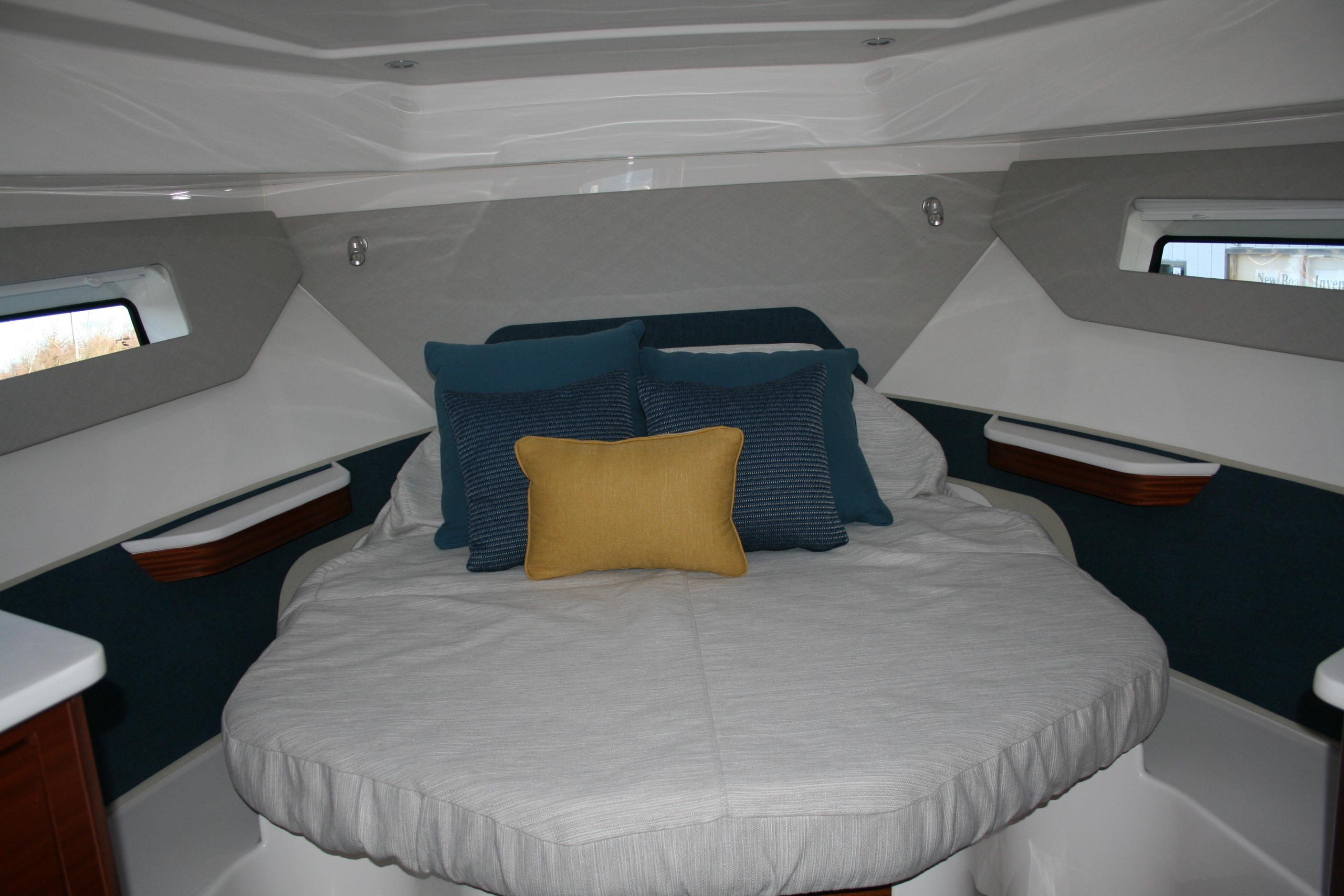 Luxurious cabin interior of 2025 Pursuit OS 405 Offshore boat with plush bedding.