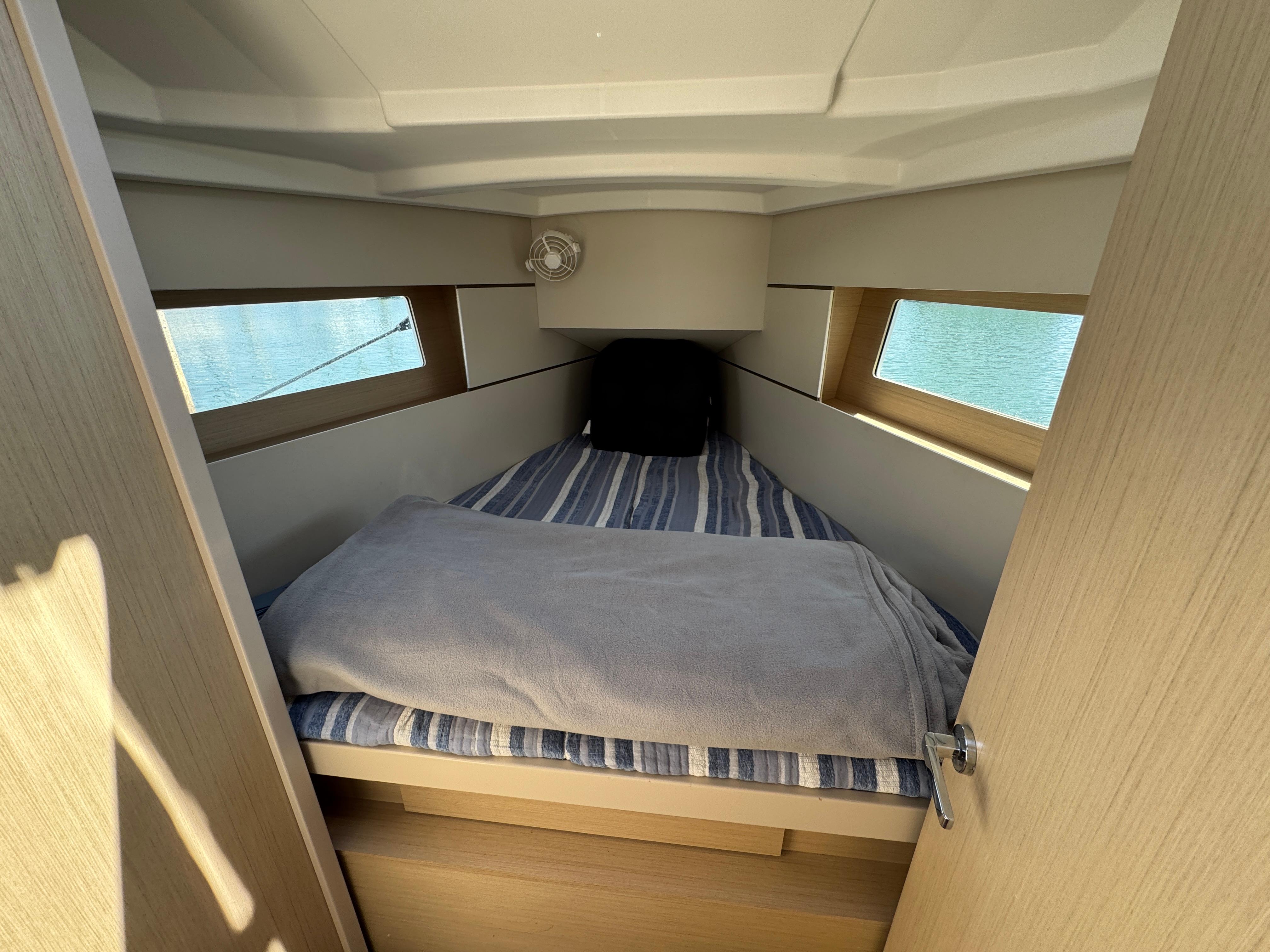 Cozy cabin interior of 2021 Beneteau Oceanis 35.1 sailboat with striped bedding.