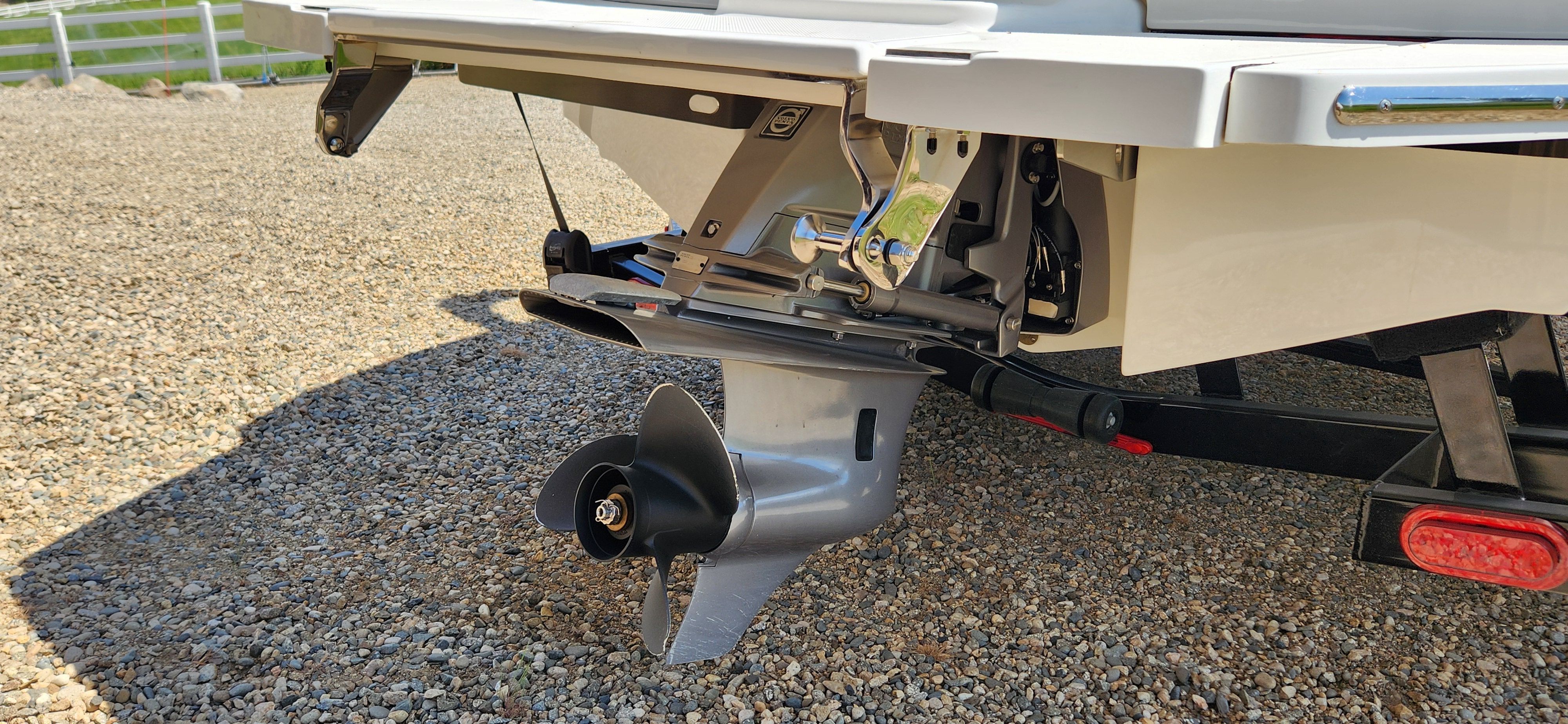 Close-up of a boat propeller on a gravel surface.