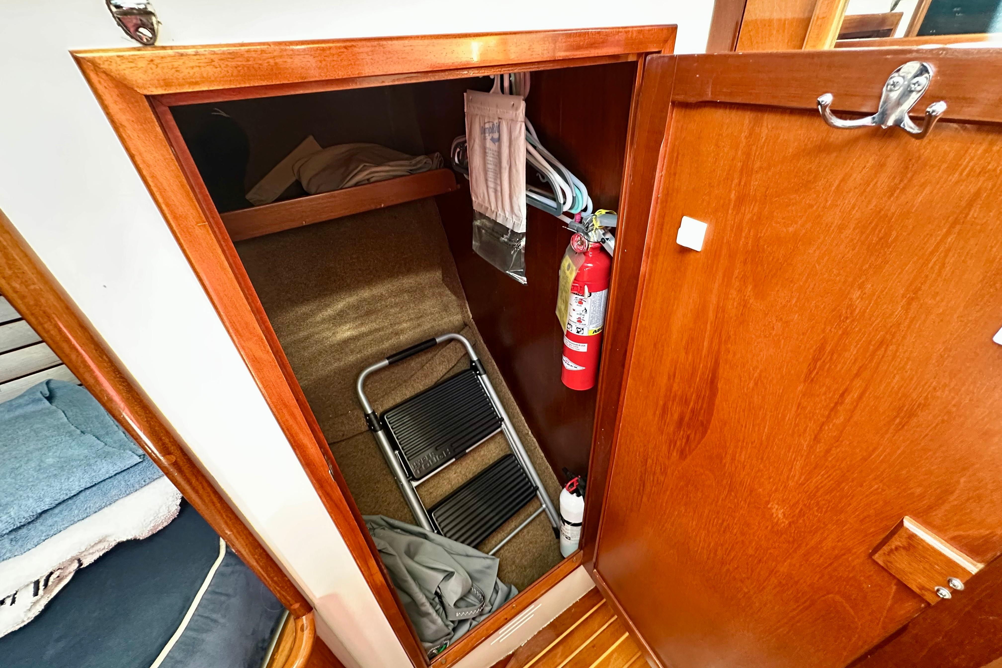 Wooden closet interior on 1982 Hinckley Bermuda 40 MK III yacht, featuring fire extinguisher and step ladder.