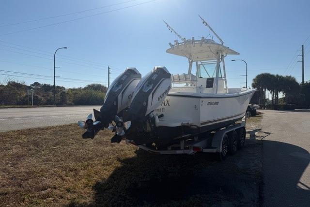 2002 Regulator 26 Forward Seating boat with dual engines on a trailer, parked roadside.