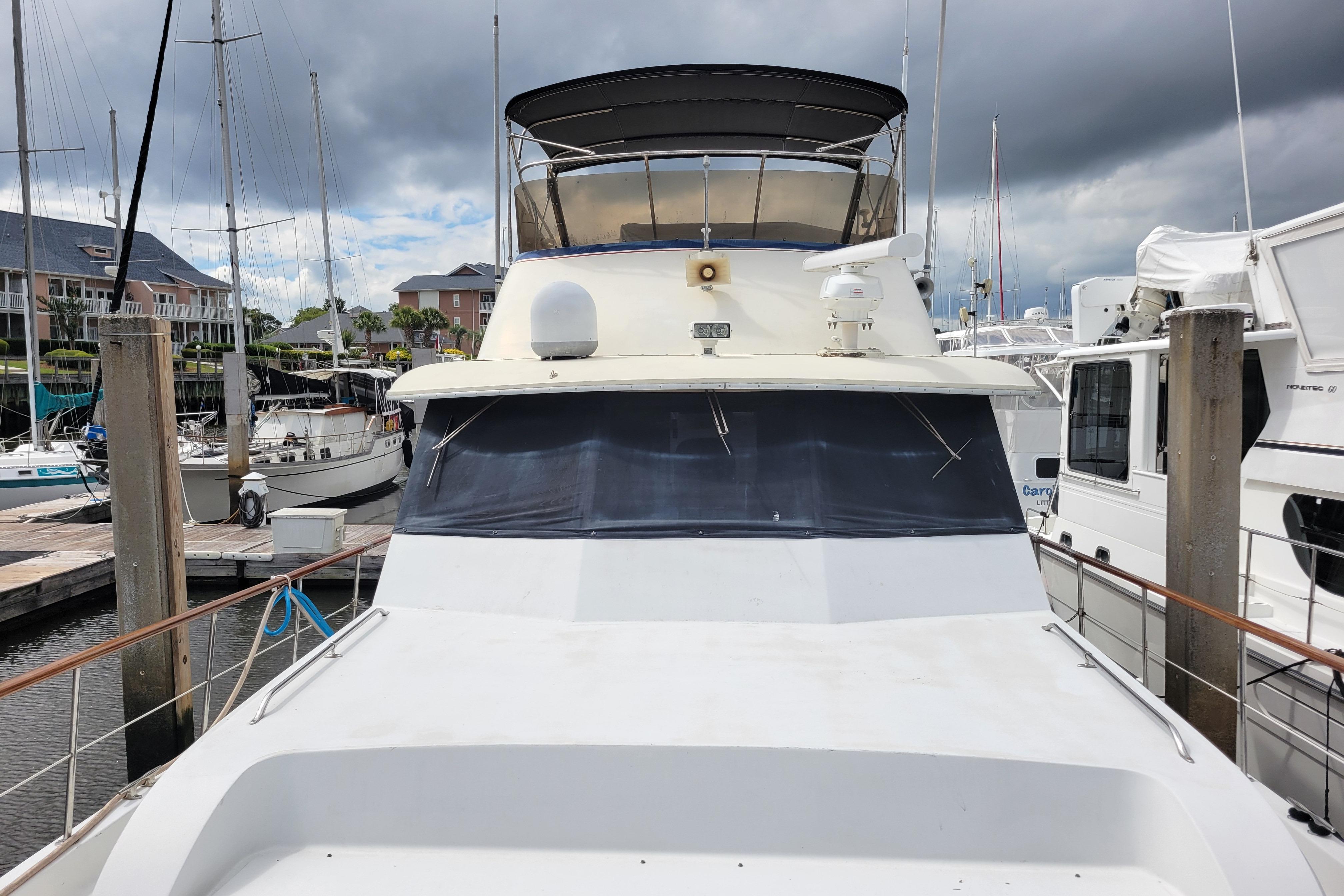 1980 Hatteras 53 Yacht Fisherman docked at marina under cloudy skies.