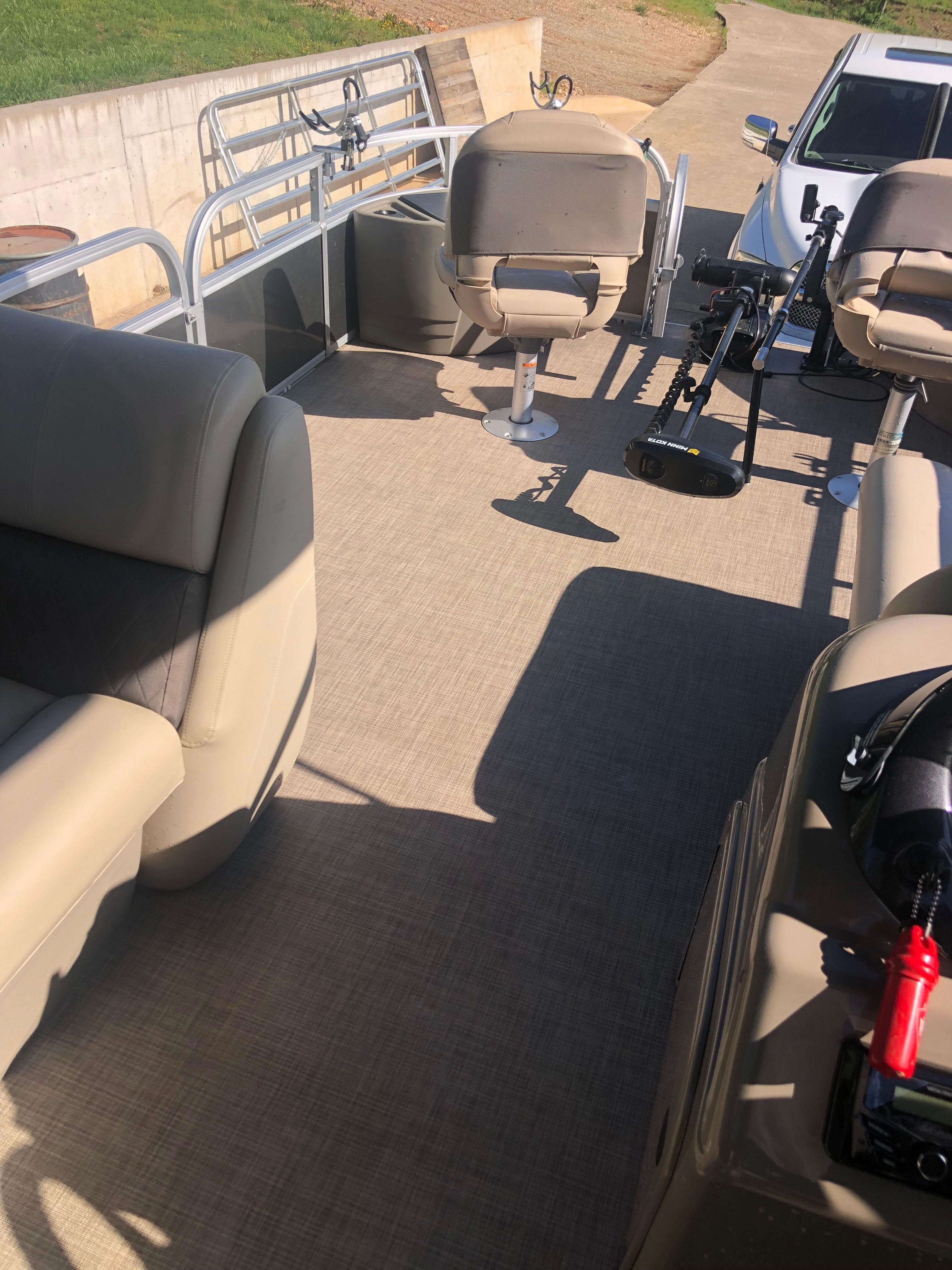 Interior view of a Sun Tracker Fishin' Barge 22 DLX with beige seats and fishing rod holders.