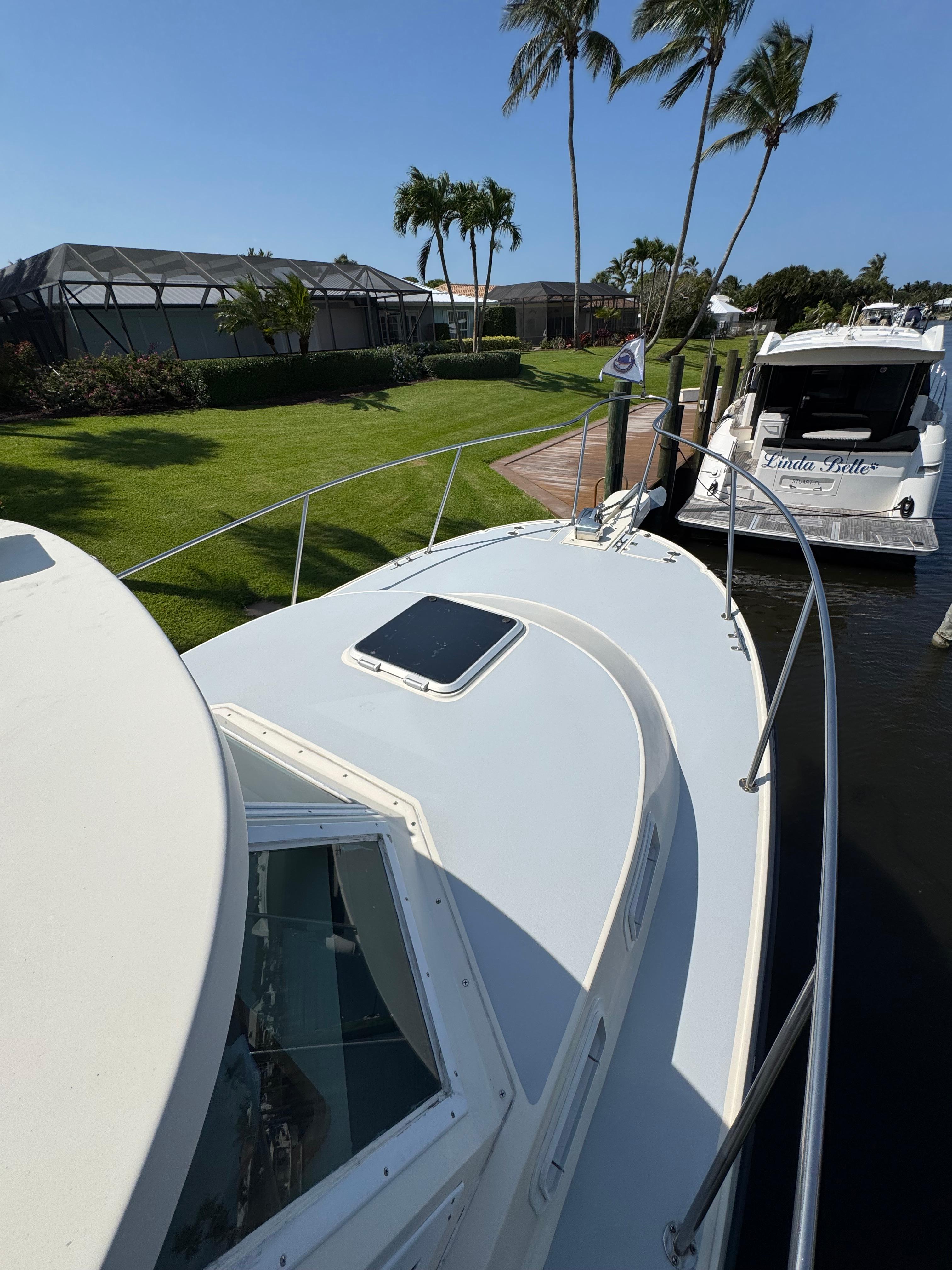 1996 Albin Tournament Express boat docked near palm trees and waterfront homes.