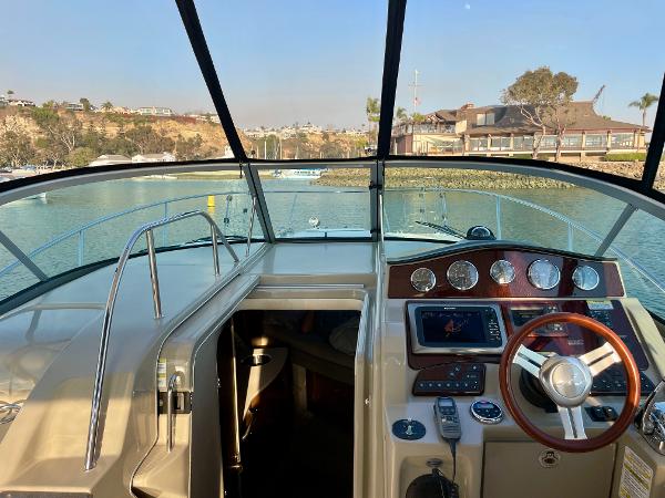 2014 Sea Ray 330 Sundancer cockpit with steering wheel and control panel, docked in a marina.