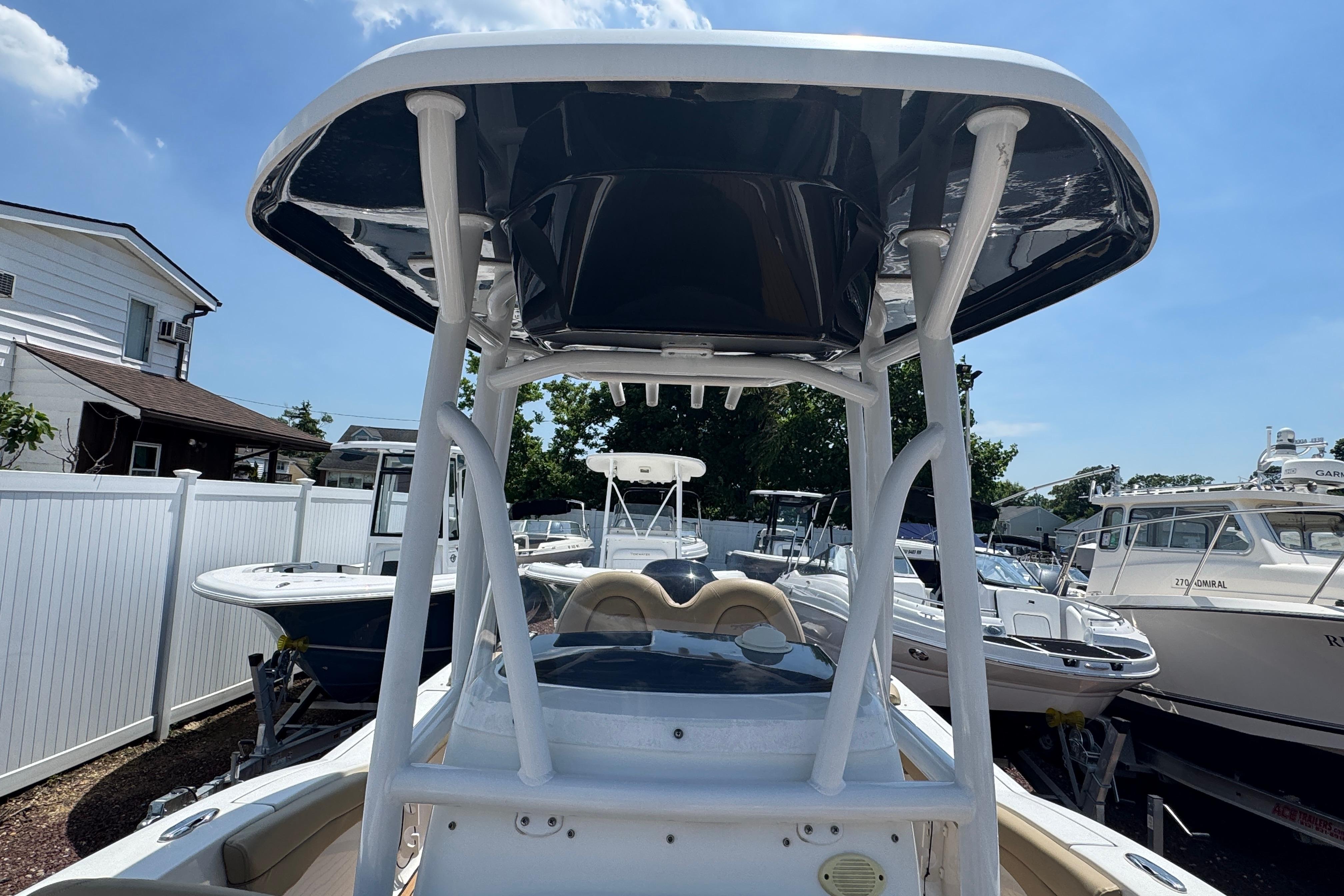 2016 Tidewater 230 LXF boat with T-top, parked in a marina under a clear sky.