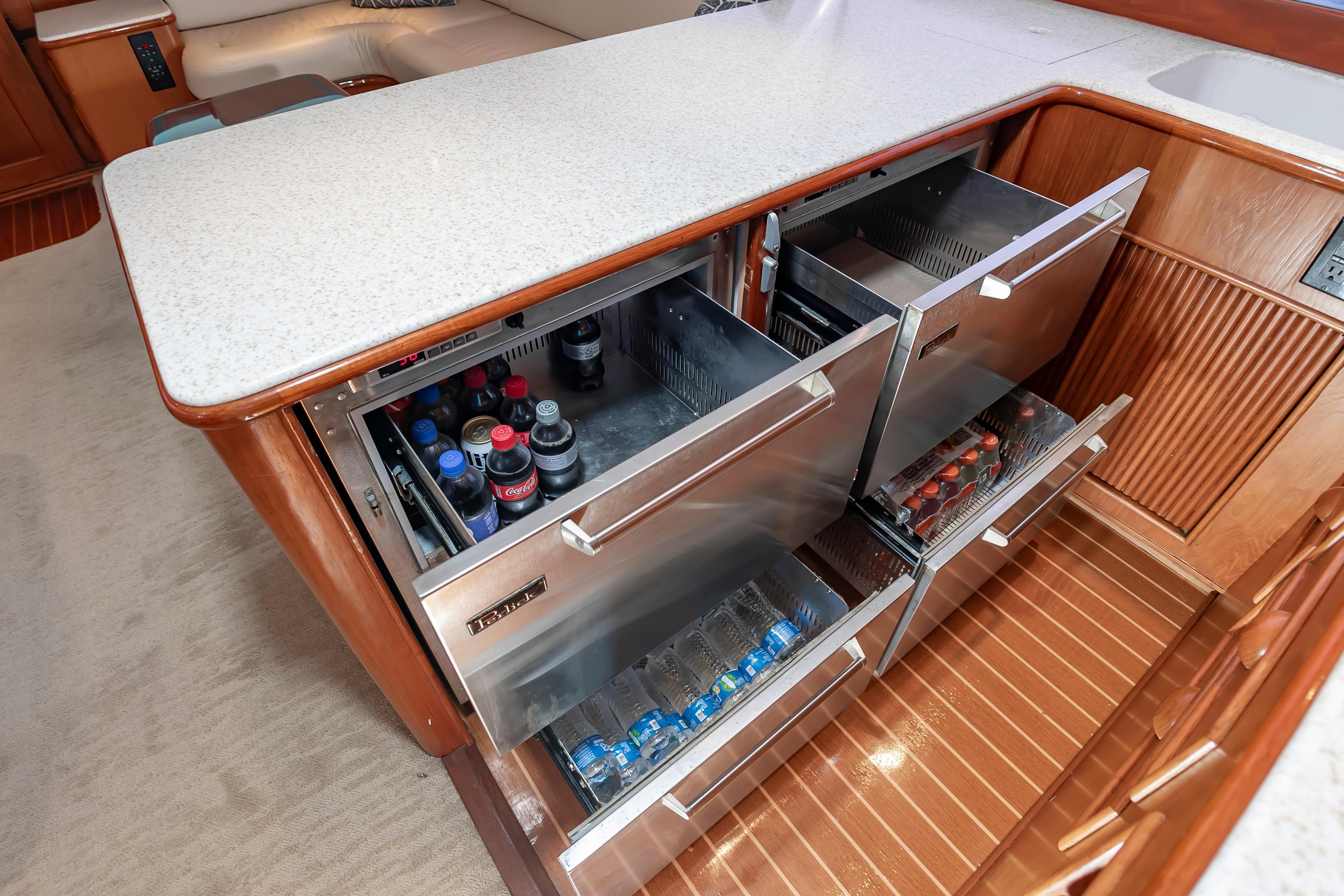 Luxury yacht galley with open stainless steel drawers, stocked with beverages, on a Custom Carolina Scarborough 56 Convertible.