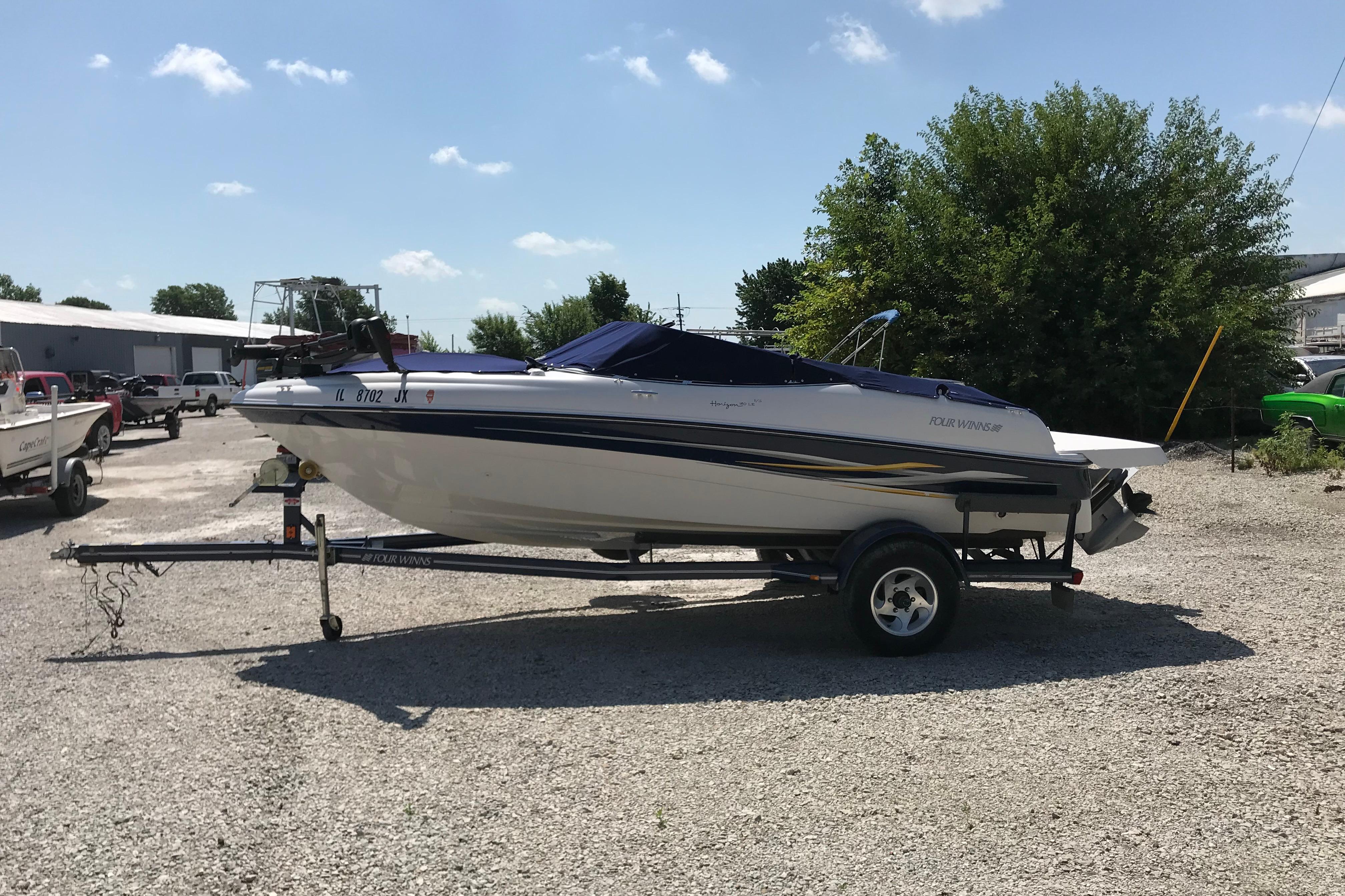 2005 Four Winns 180 Horizon FS boat on trailer, parked outdoors on gravel.