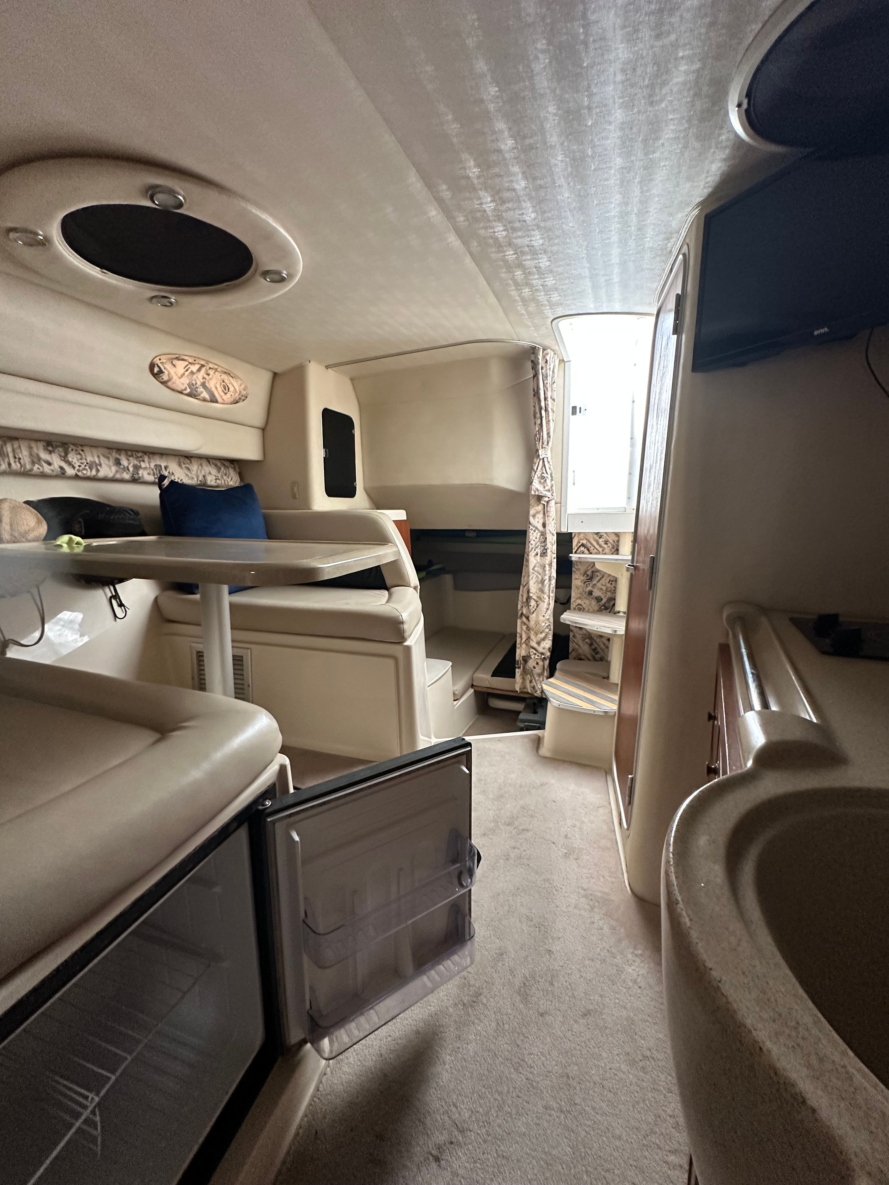 Interior of a 1999 Wellcraft 3000 Martinique yacht with seating area and fridge.
