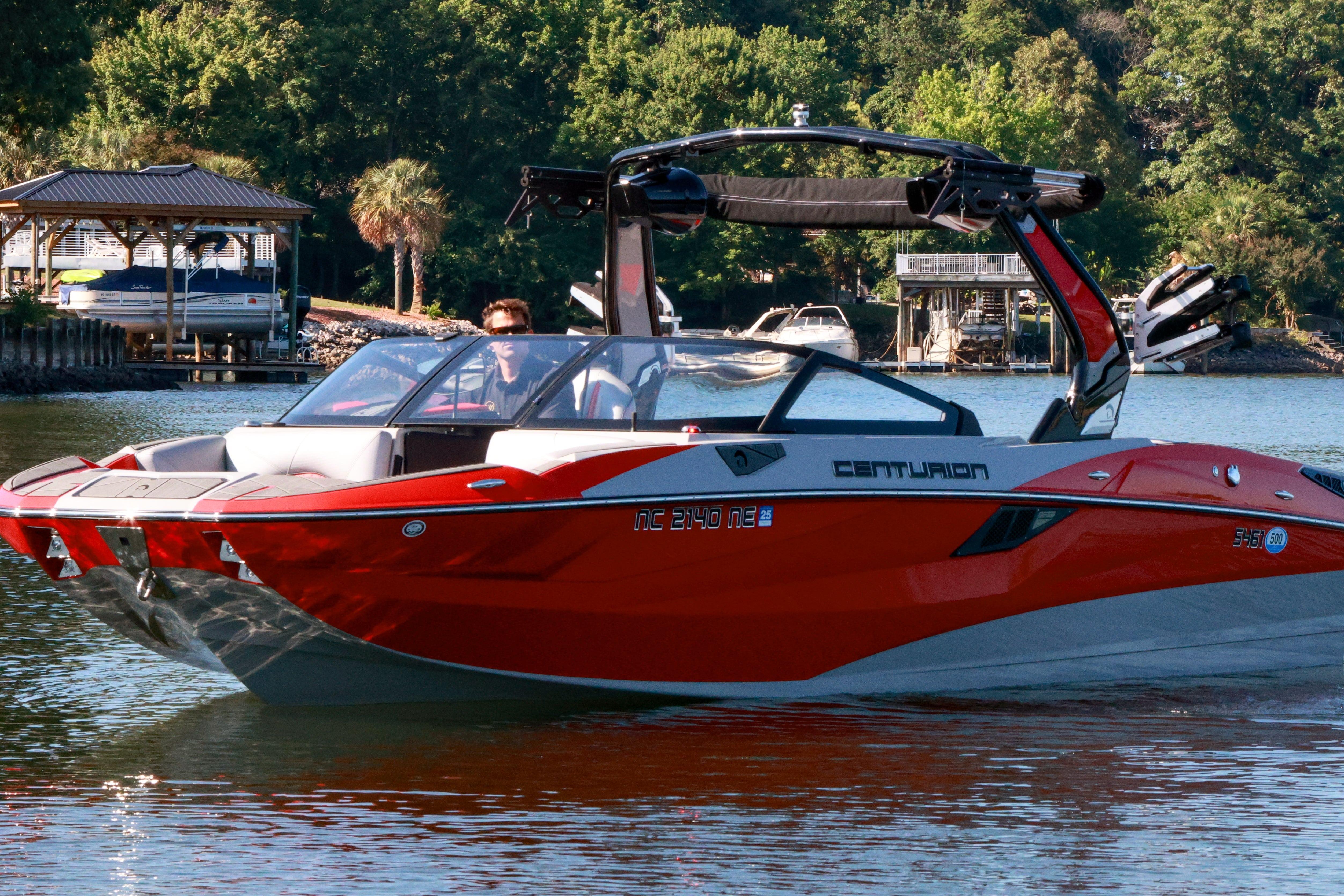 2024 Centurion Fi23 boat cruising on a serene lake with lush greenery in the background.
