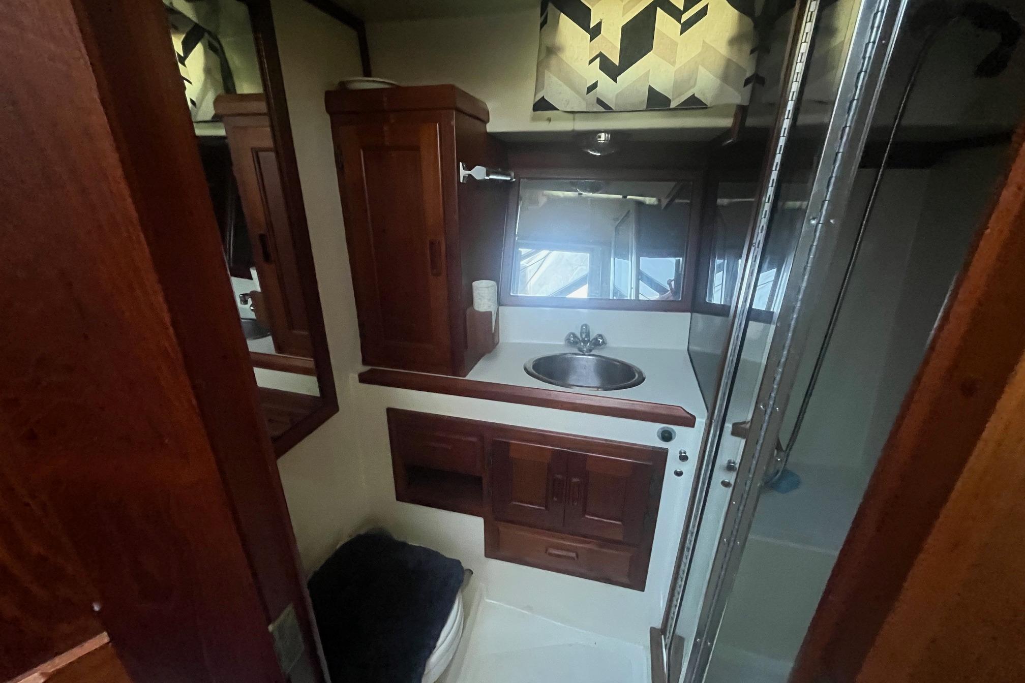 Bathroom interior of 1990 Cooper Prowler 35 with wooden cabinets and sink.