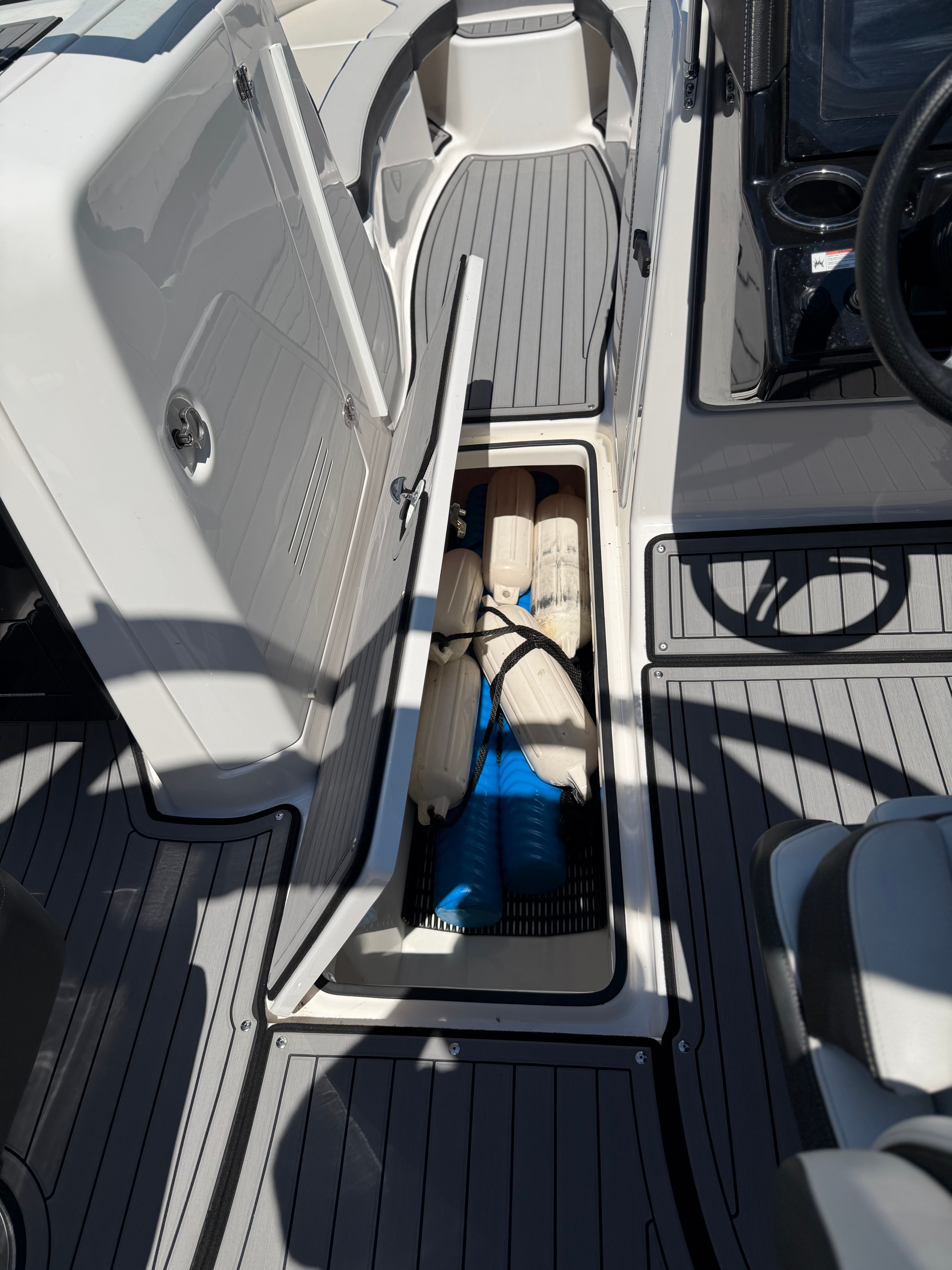 An open storage compartment on a boat reveals fenders and ropes.
