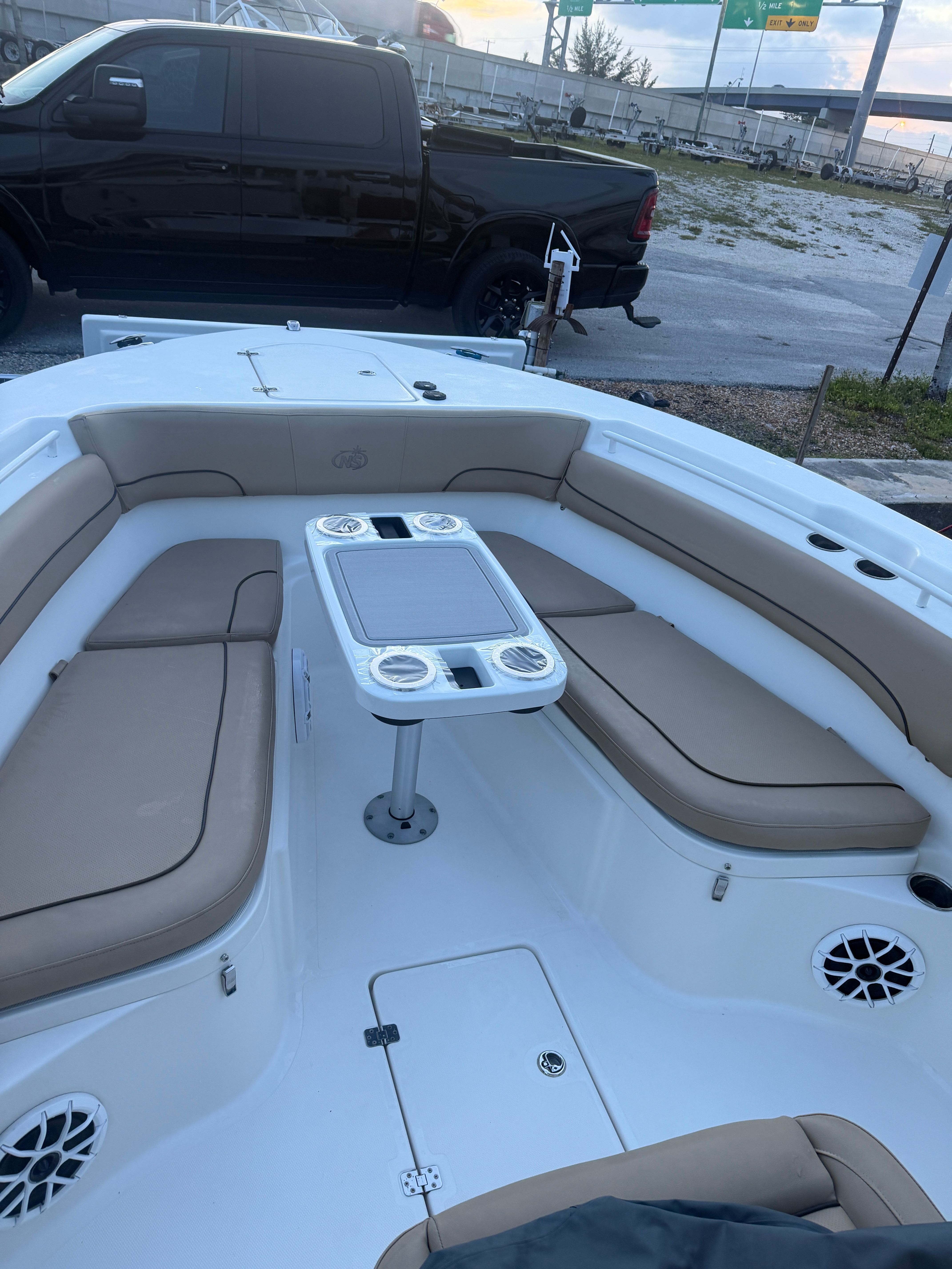 The image shows the cockpit of a 2019 NauticStar 28 XS with beige cushions and a table.
