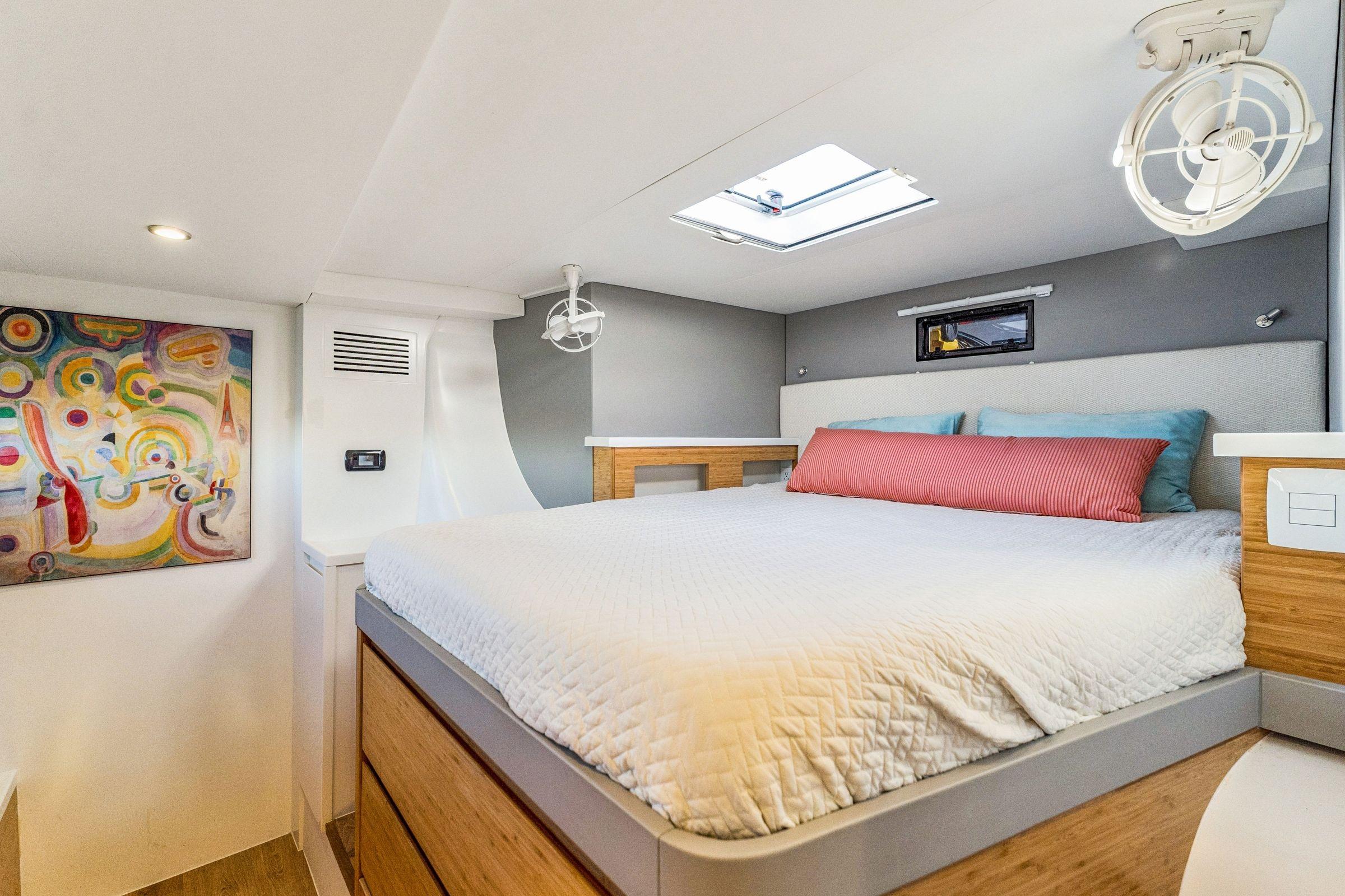 Modern bedroom interior in 2024 Balance 482 yacht, featuring colorful artwork and skylight.