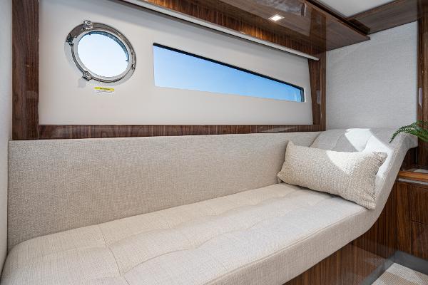 2021 Riviera 5400 Sport Yacht interior cabin with beige sofa and porthole window.