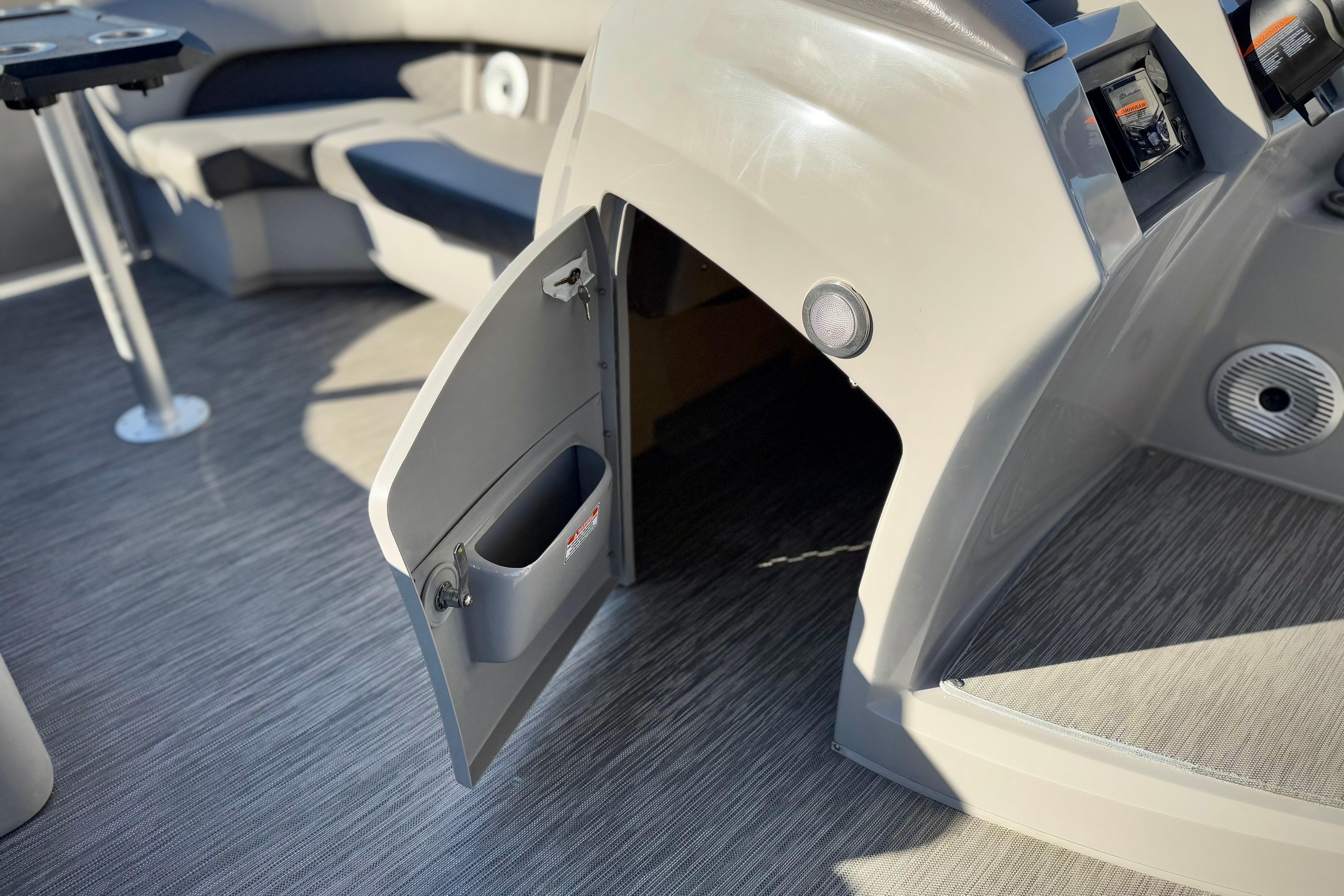 Open storage compartment on 2021 Bennington 23LSR boat with seating and table visible.