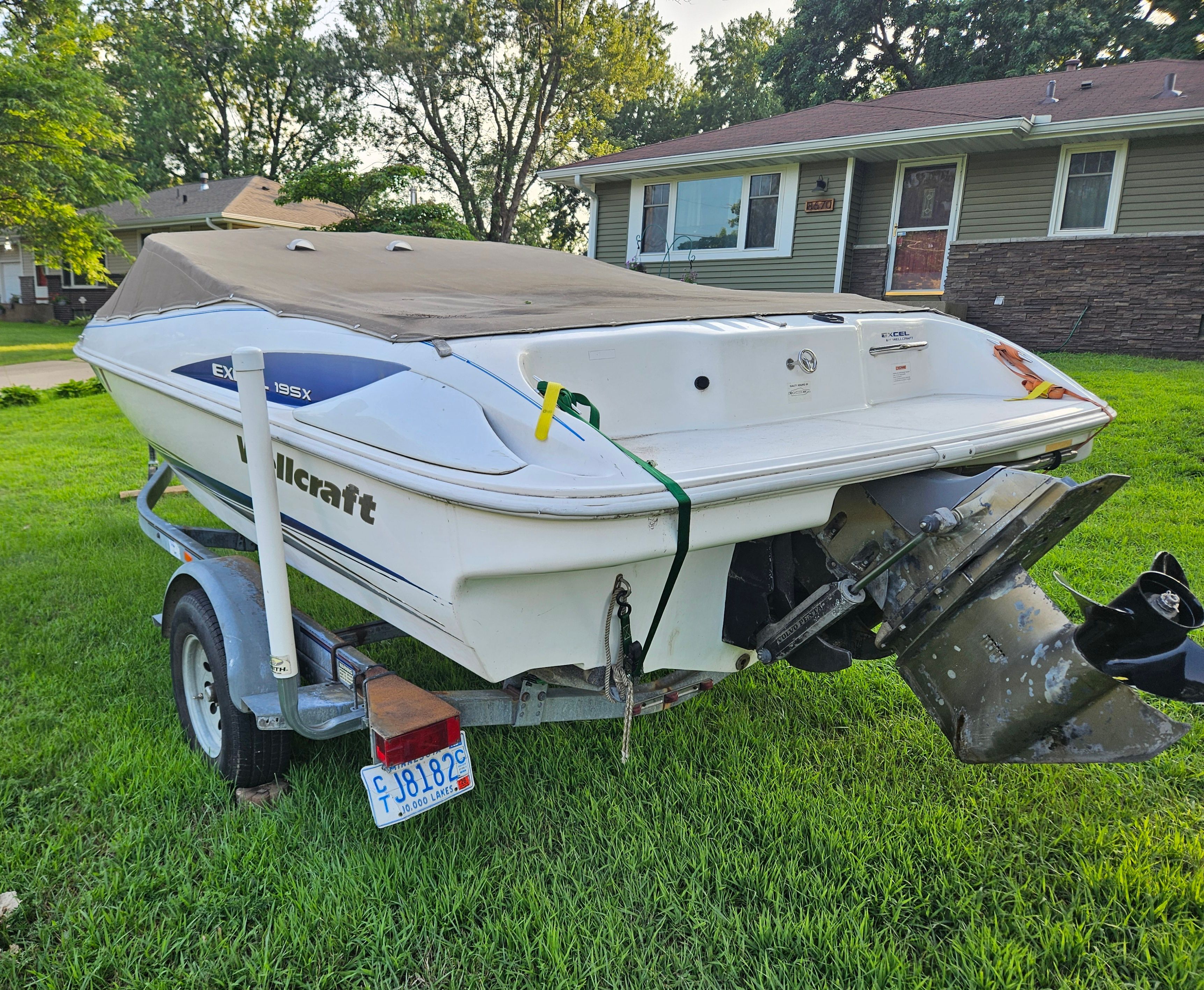 A 1996 Wellcraft Excel boat on a trailer in a grassy yard.