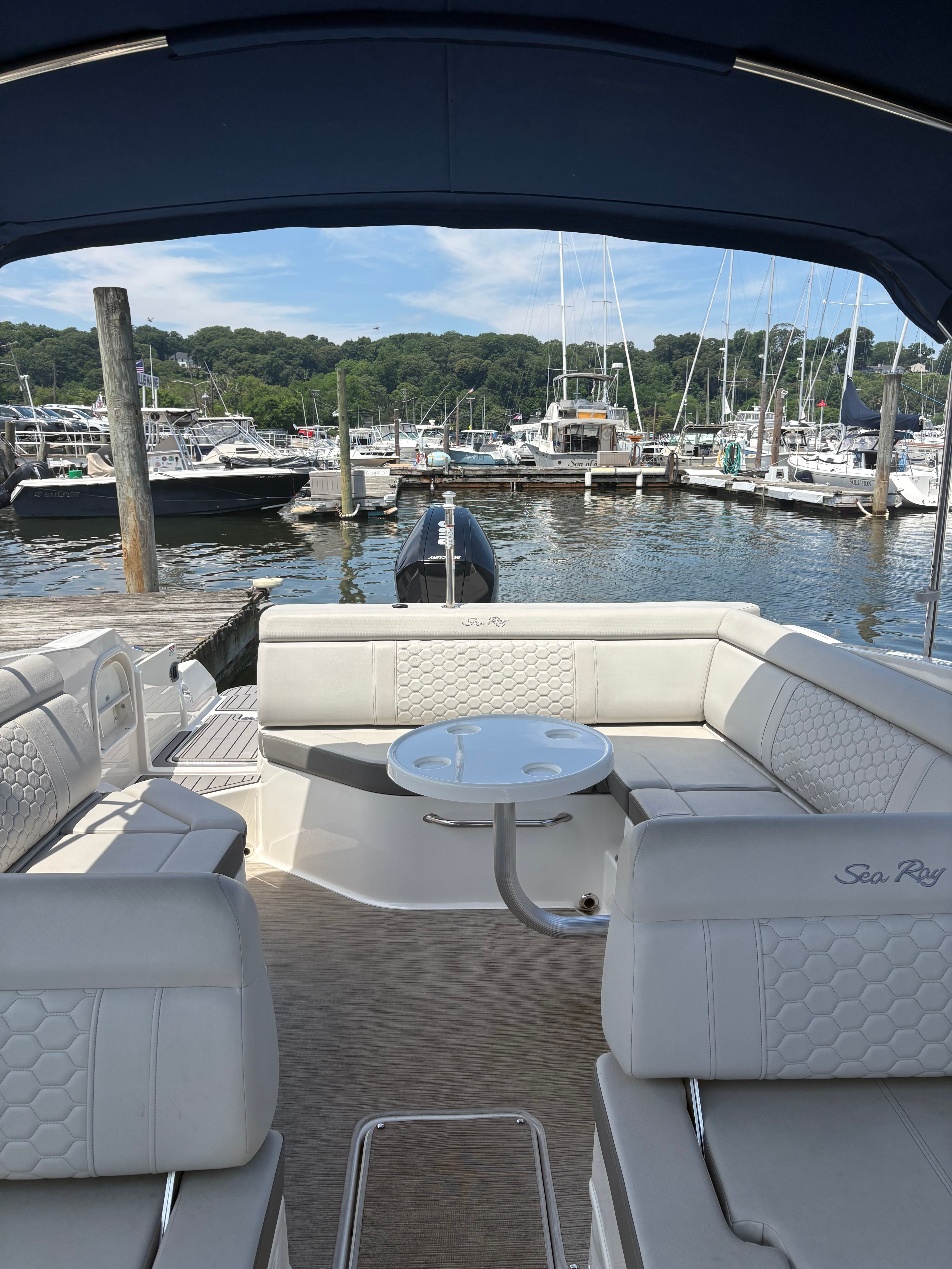 Interior of a Sea Ray SDX 270 Outboard with white seating and table, docked at a marina.