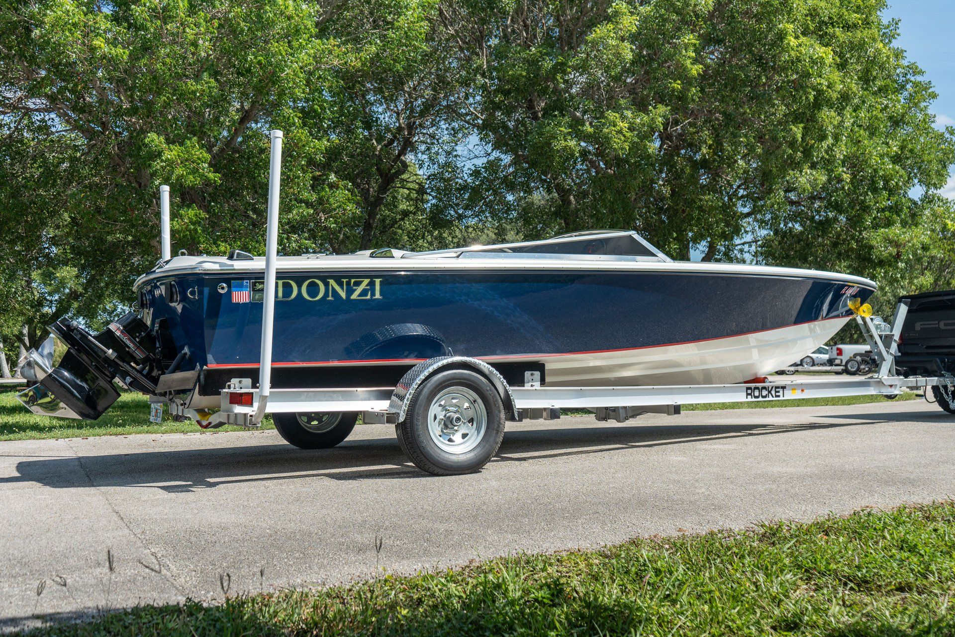 A blue 1995 Donzi 22 Classic on a trailer, surrounded by trees.