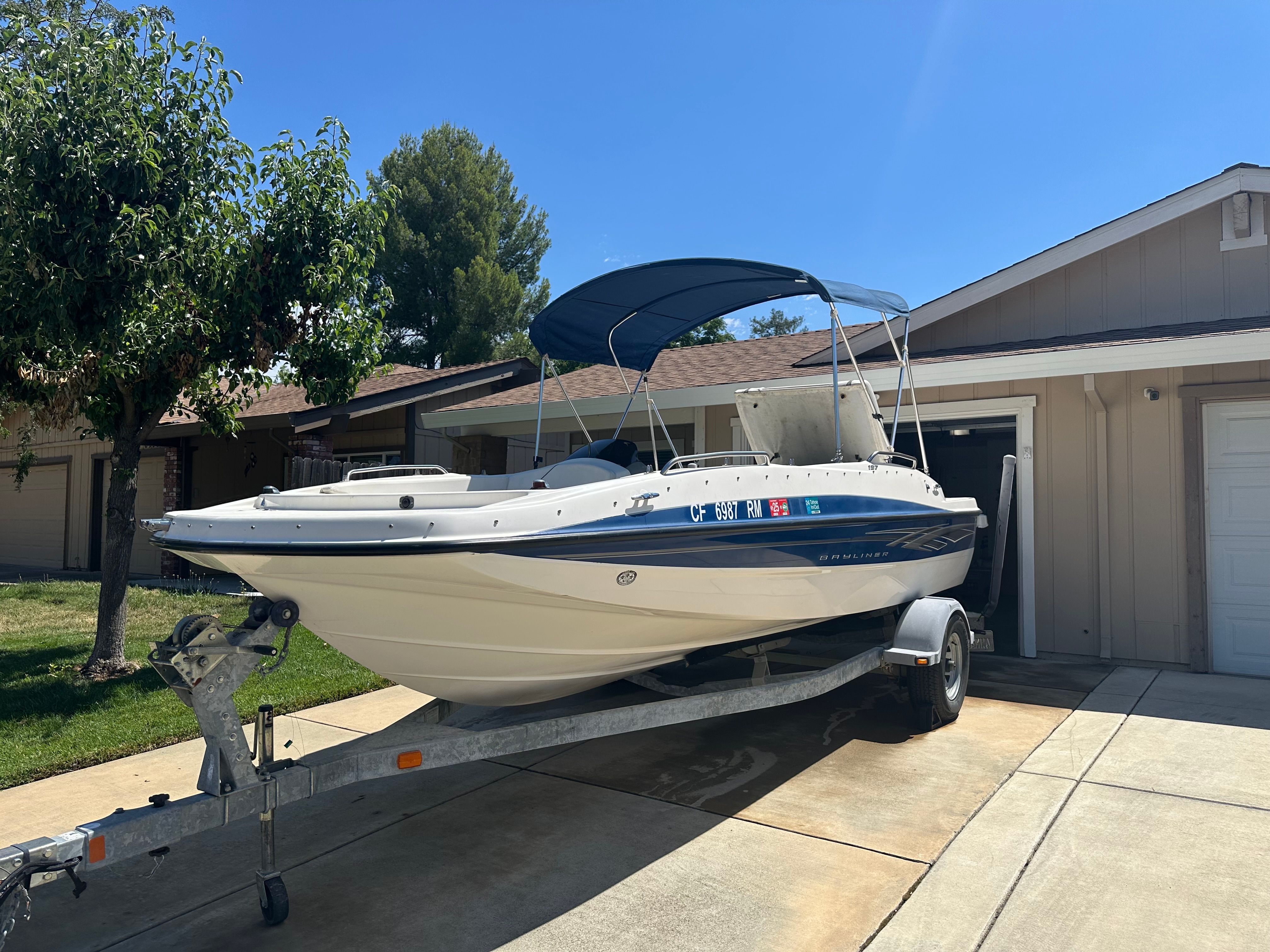 A 2008 Bayliner boat is on a trailer in a driveway.
