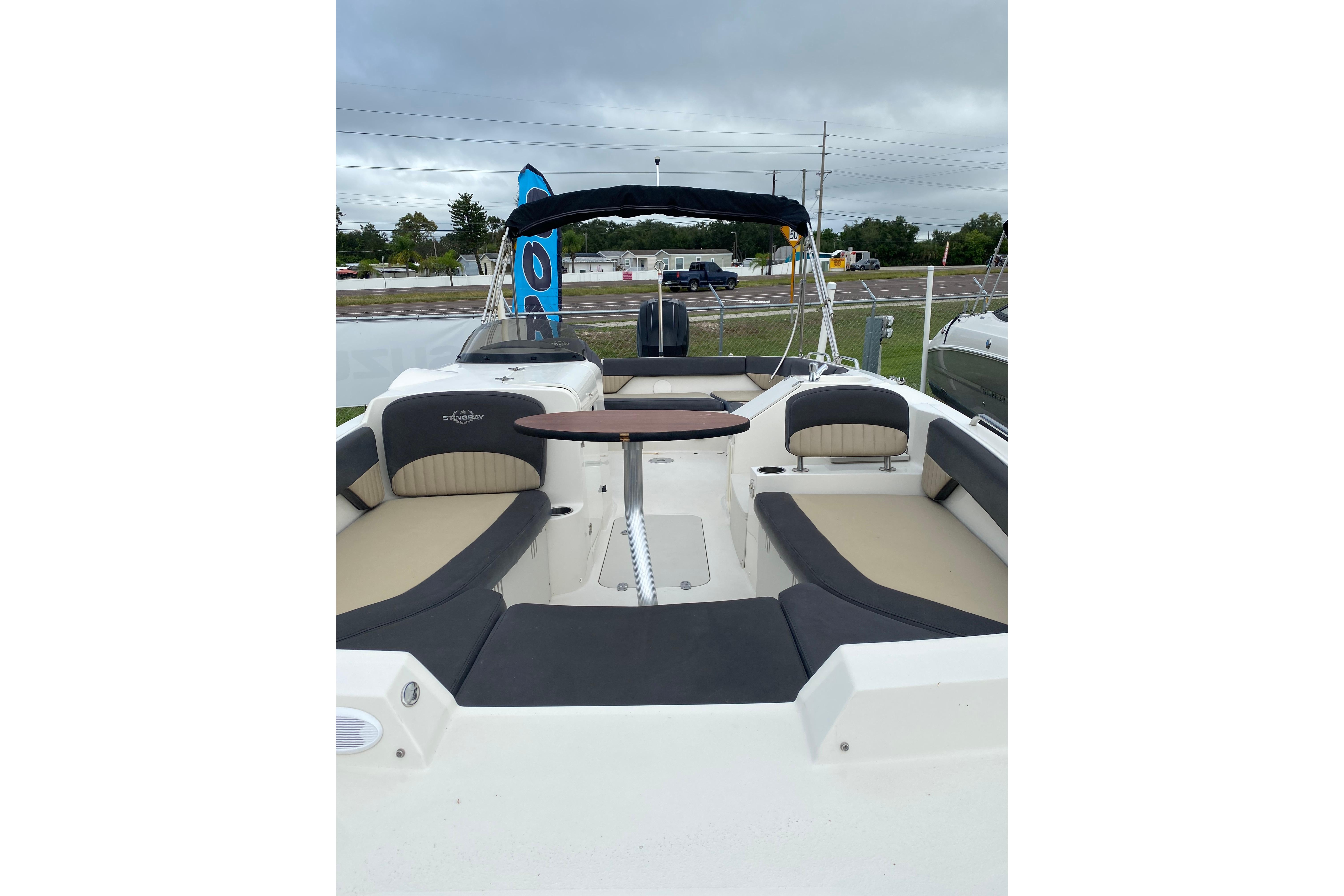 2018 Stingray 212 SC boat interior with seating and table, displayed outdoors.