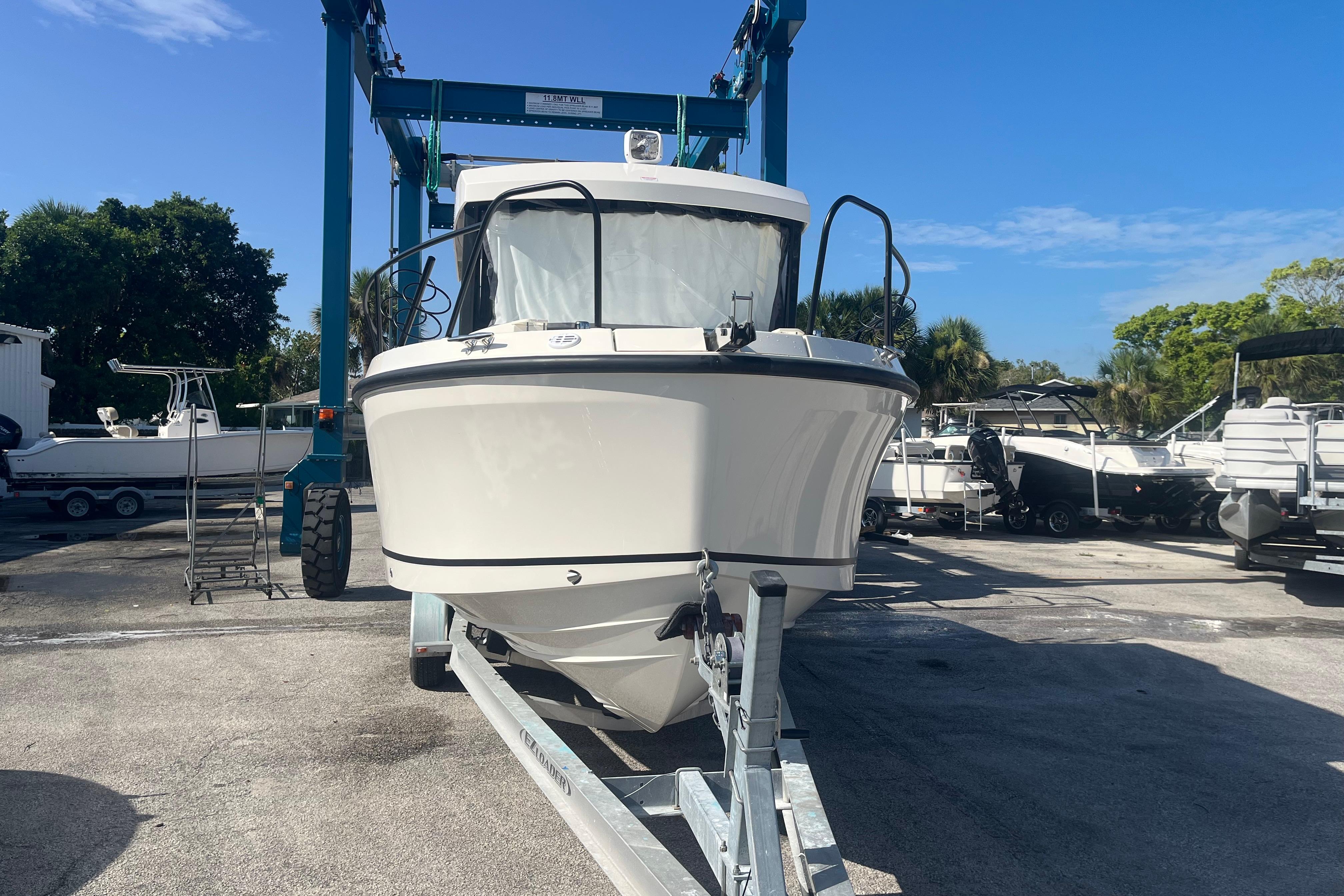 2025 Bayliner Trophy T25 Pilothouse boat on trailer in marina setting.