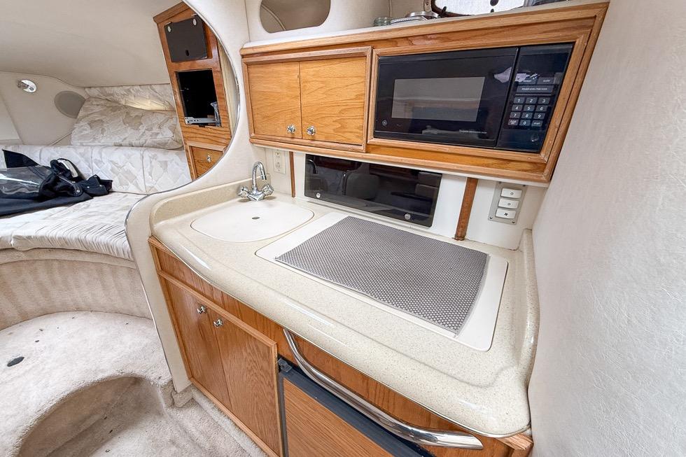 1999 Sea Ray 290 Sundancer cabin with kitchenette, sink, and microwave.